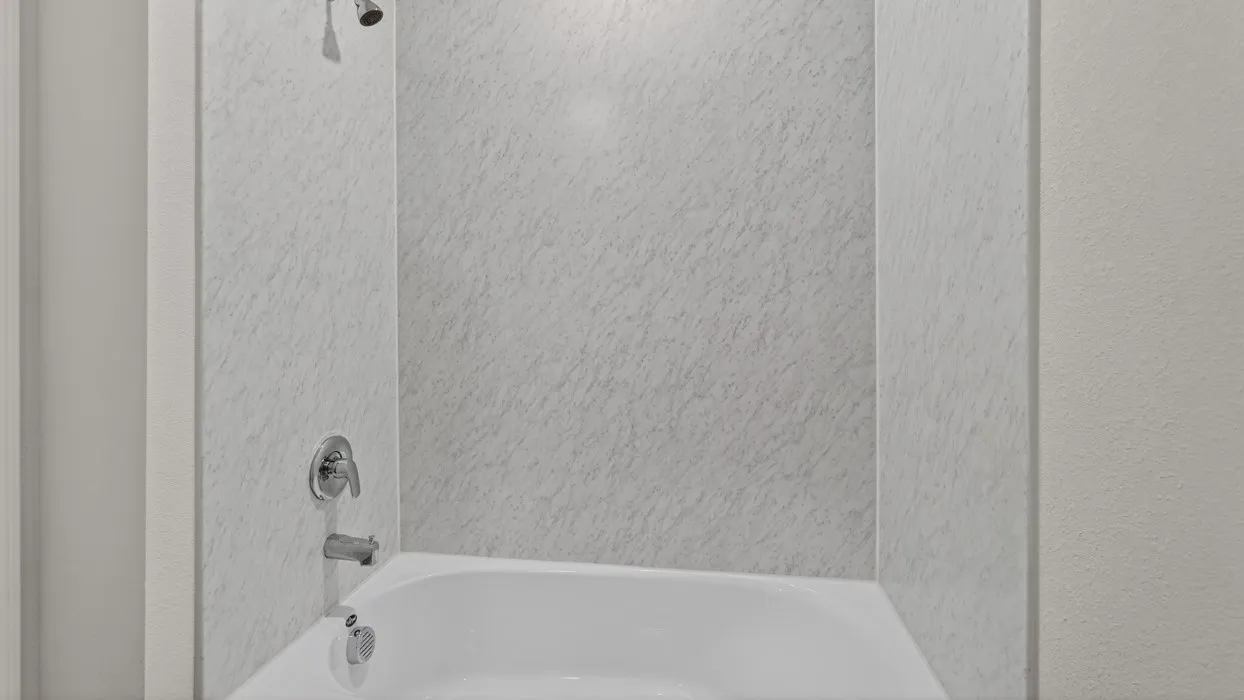 White tub-shower combination featuring a chrome shower head and faucet
