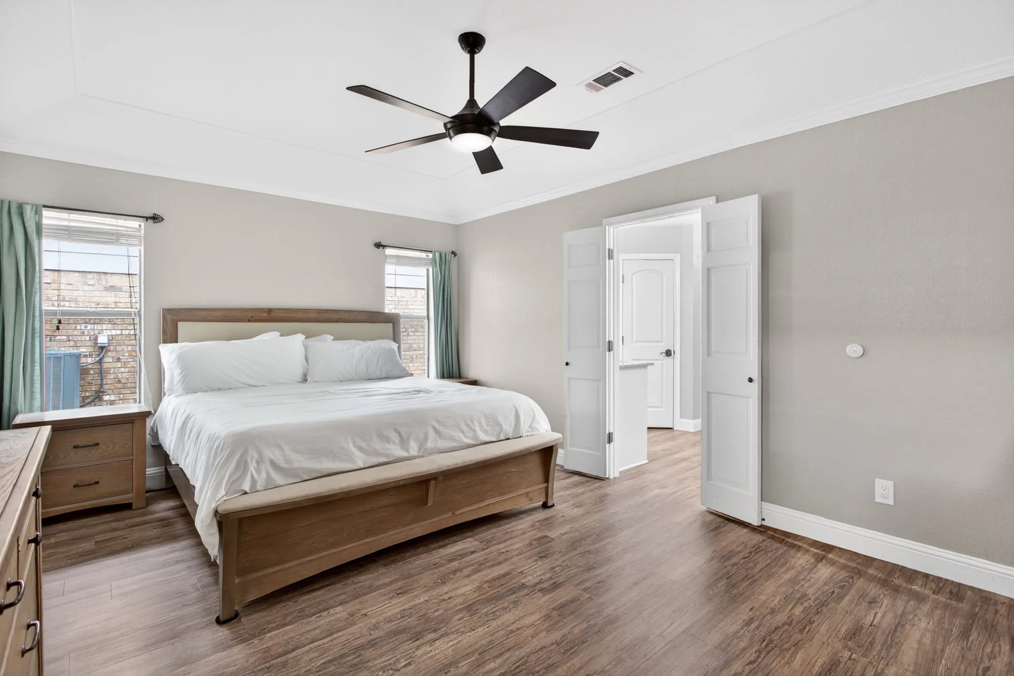 Spacious room featuring wood-finish flooring, light gray walls, and crown molding