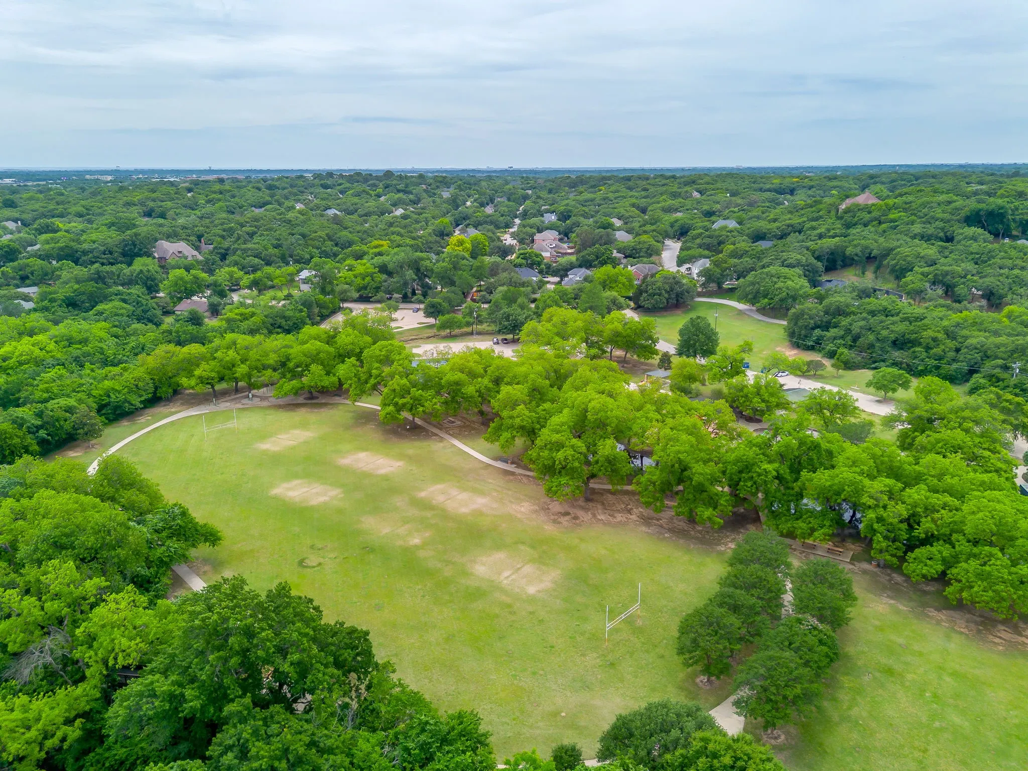 Soccer fields and walking trails - Expansive green space featuring large grassy areas, mature trees, and winding walking paths