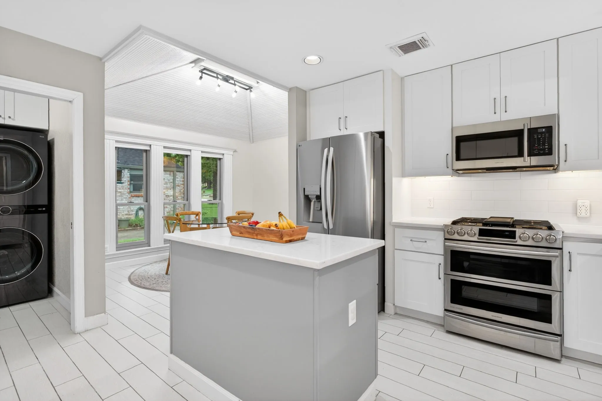Modern kitchen featuring white cabinetry, stainless steel appliances, a center island with a light-toned countertop, and wood-finish flooring