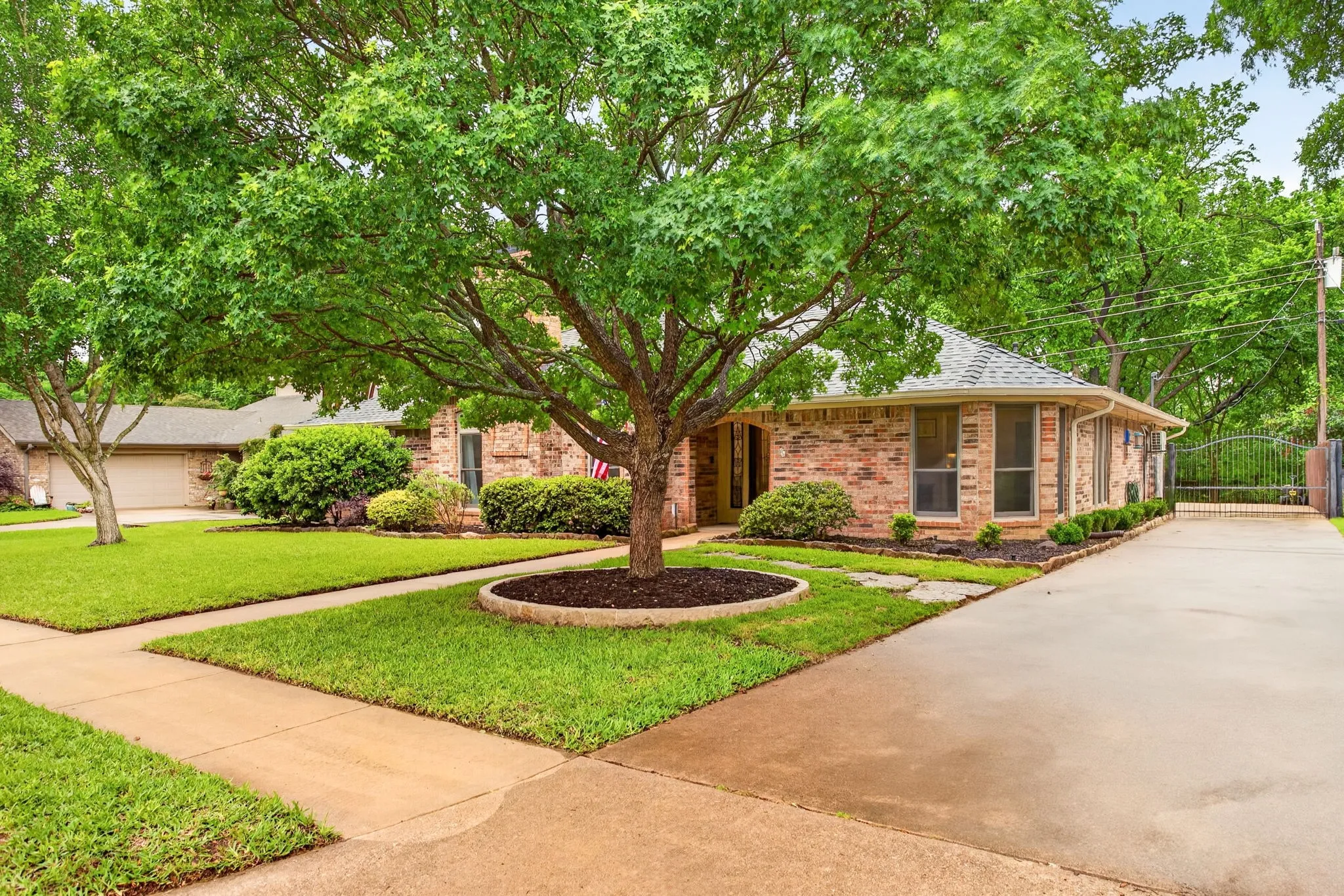 Brick exterior with rear facing garage, a gabled roof and mature trees