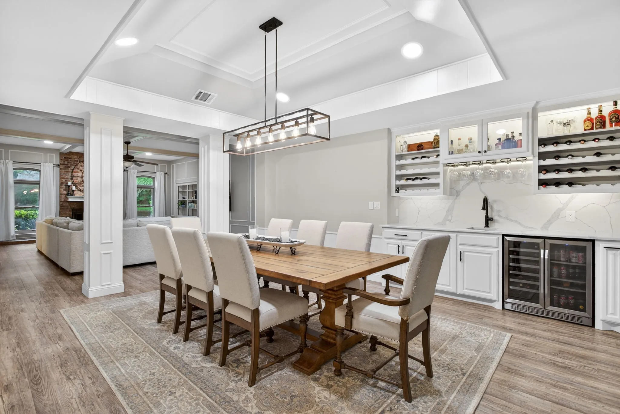 Dining area featuring a coffered ceiling, wood-finish flooring, and a built-in wet bar with quartz countertops and under-cabinet lighting