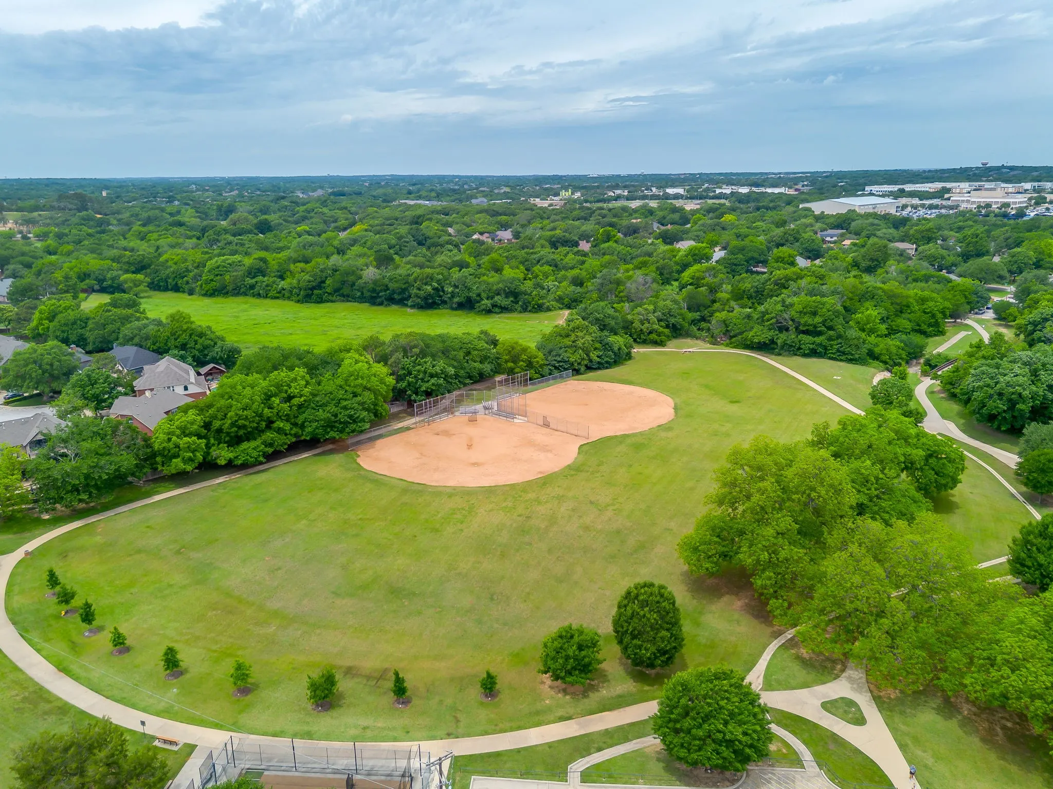 Baseball fields - Expansive green space featuring a baseball field, mature trees, and paved walking paths