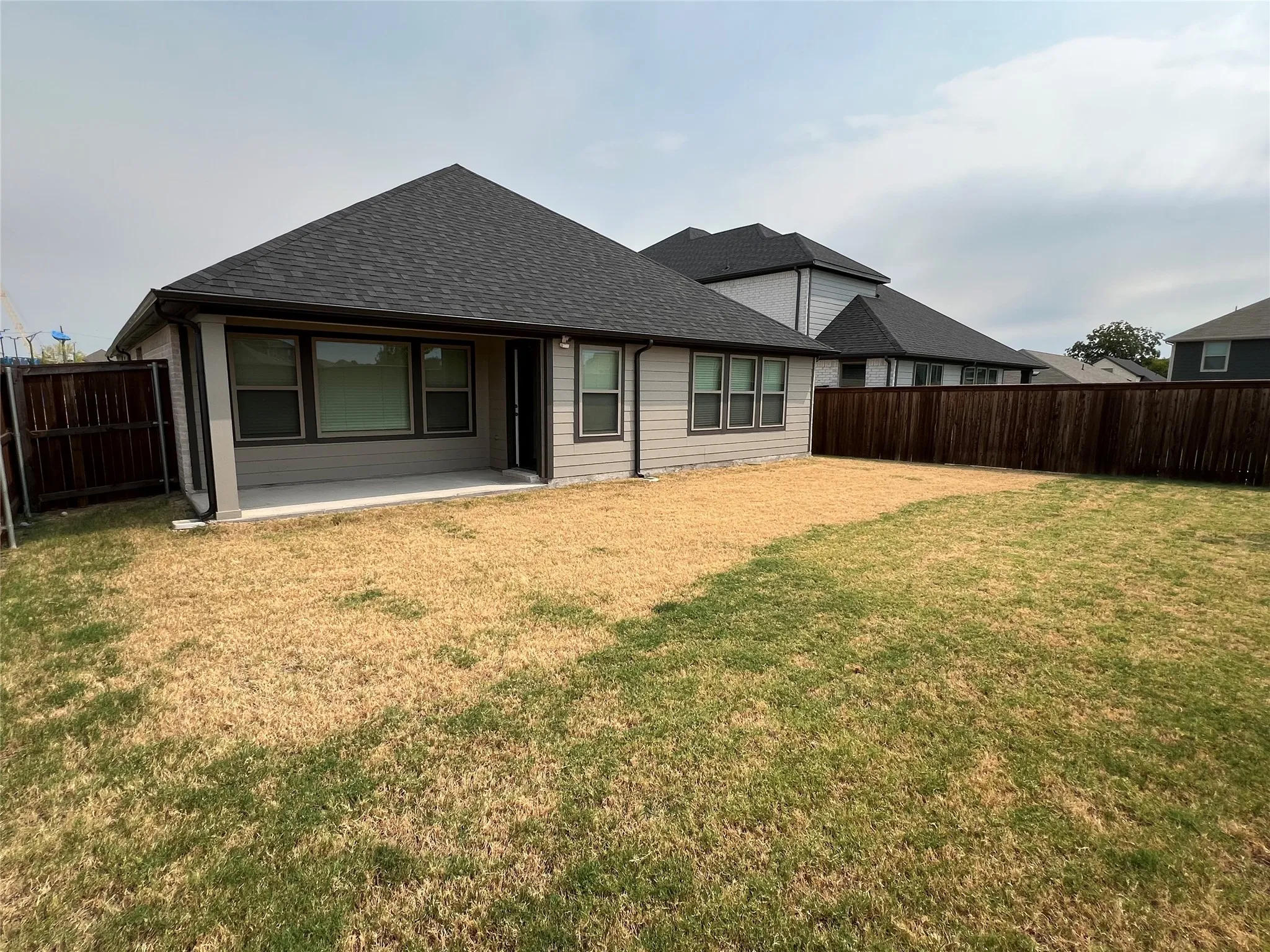 Expansive rear yard featuring a freshly seeded lawn with mature landscaping and wooden privacy fencing