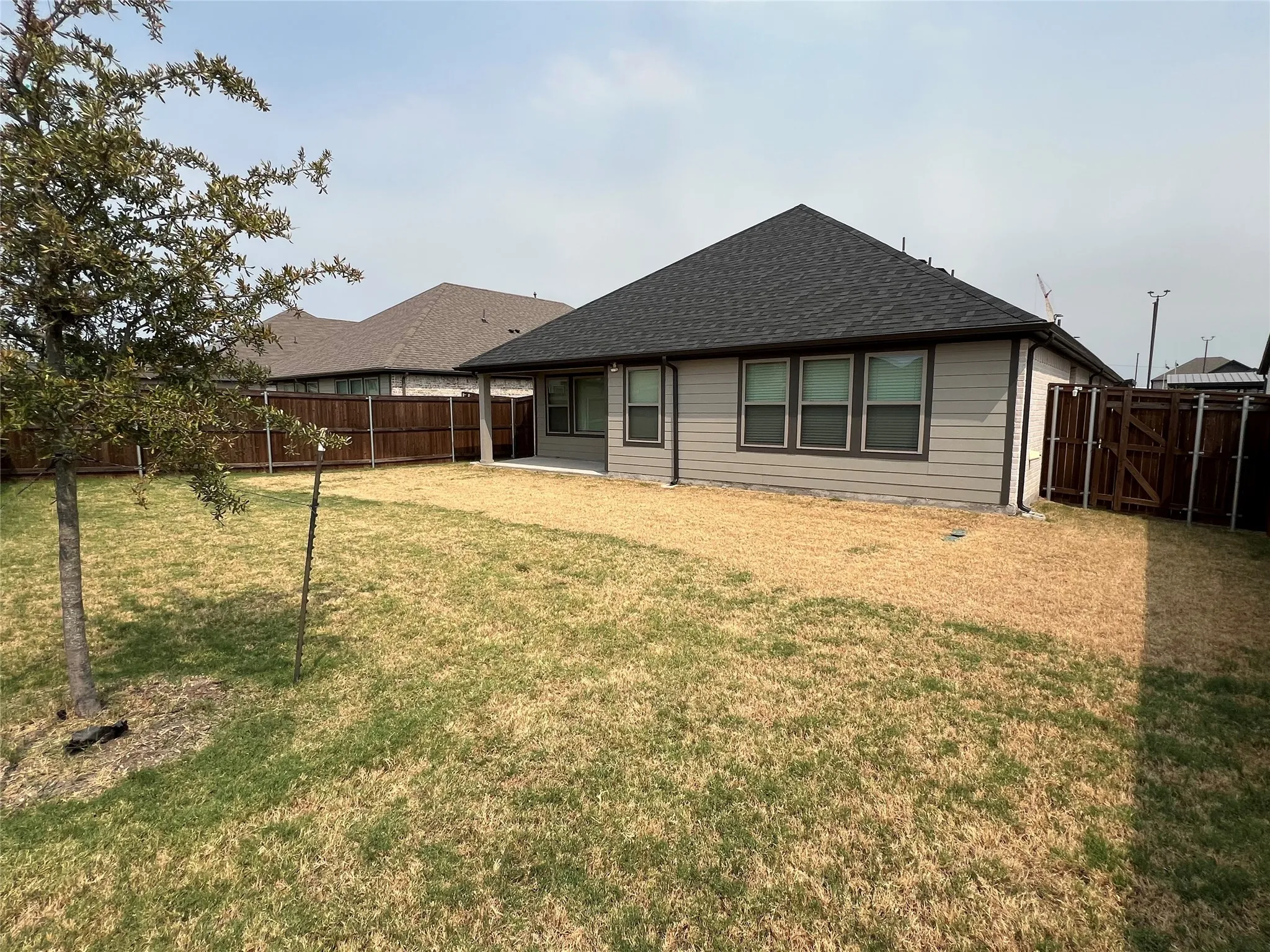 Exterior siding with multiple windows, covered patio, and wood fencing