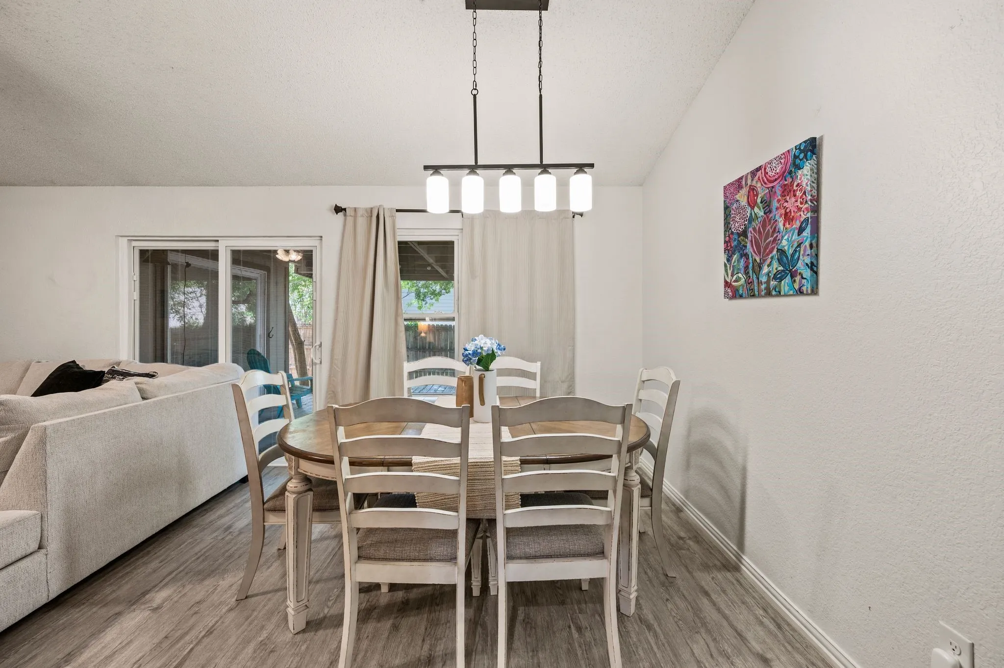 Dining area featuring wood-finish flooring, a linear chandelier, and sliding glass doors leading to the exterior