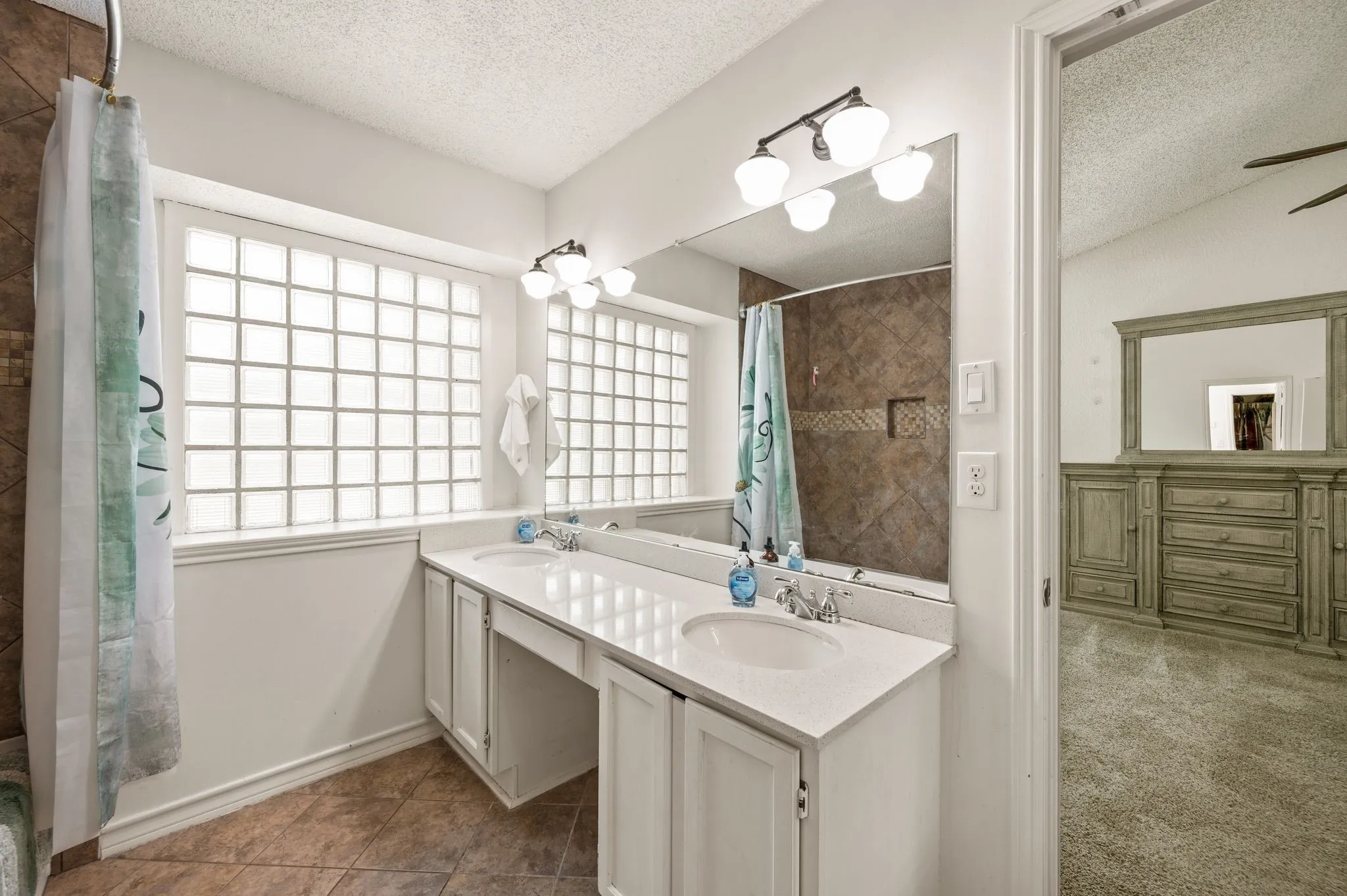 Spa-inspired primary bathroom featuring a spacious dual-sink vanity with white cabinetry, quartz countertop, and chrome fixtures