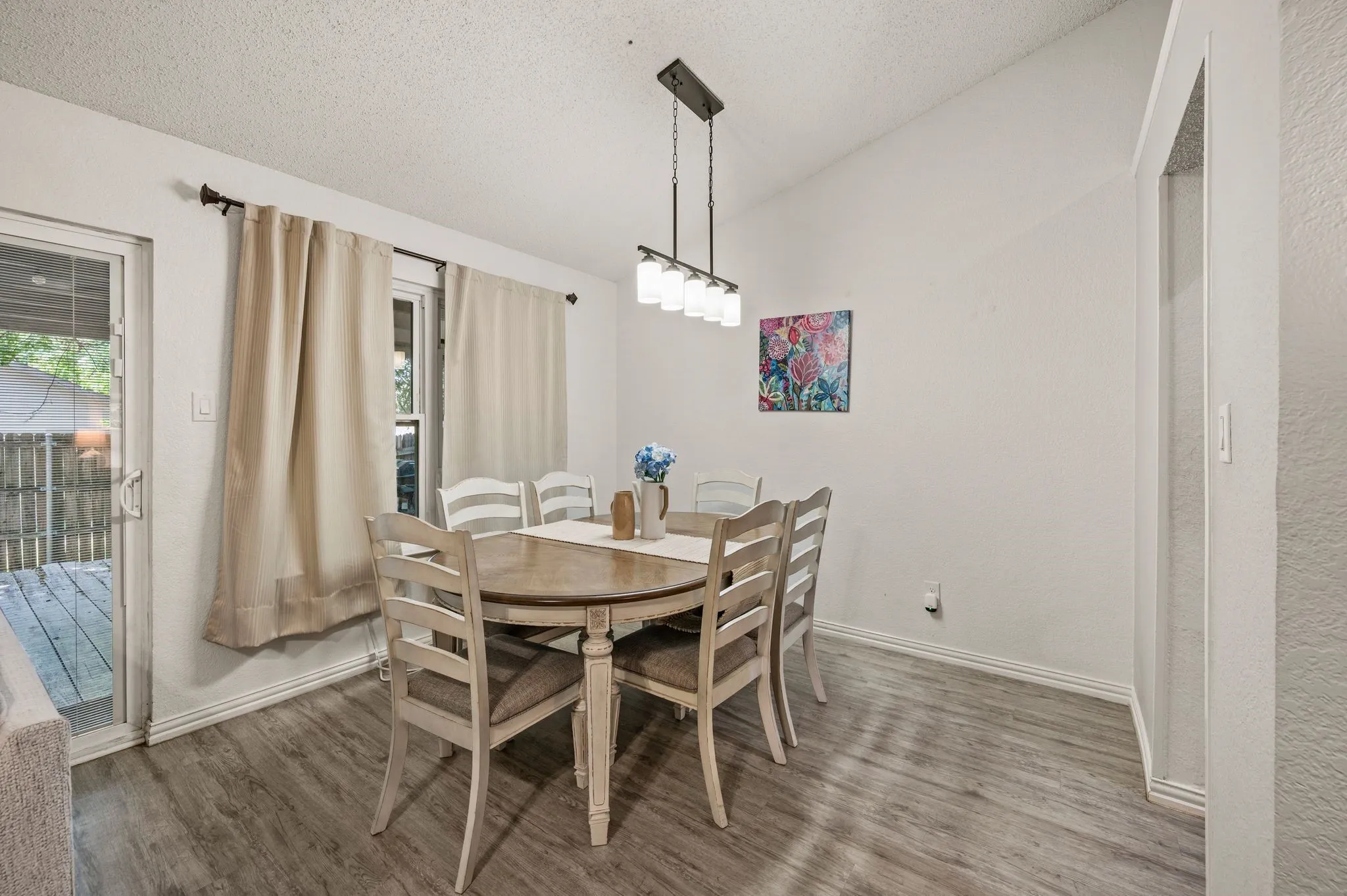 Dining area featuring wood-finish flooring, vaulted ceiling, and a modern linear chandelier