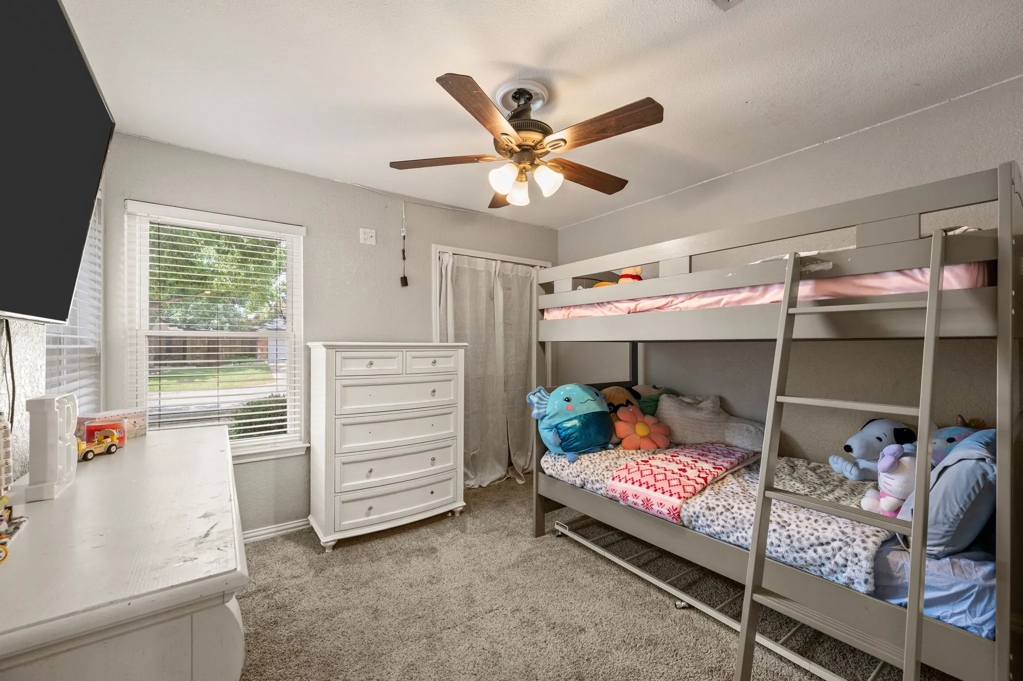 Carpeted room featuring a ceiling fan with light fixture, a window with horizontal blinds, and a built-in closet with privacy curtain