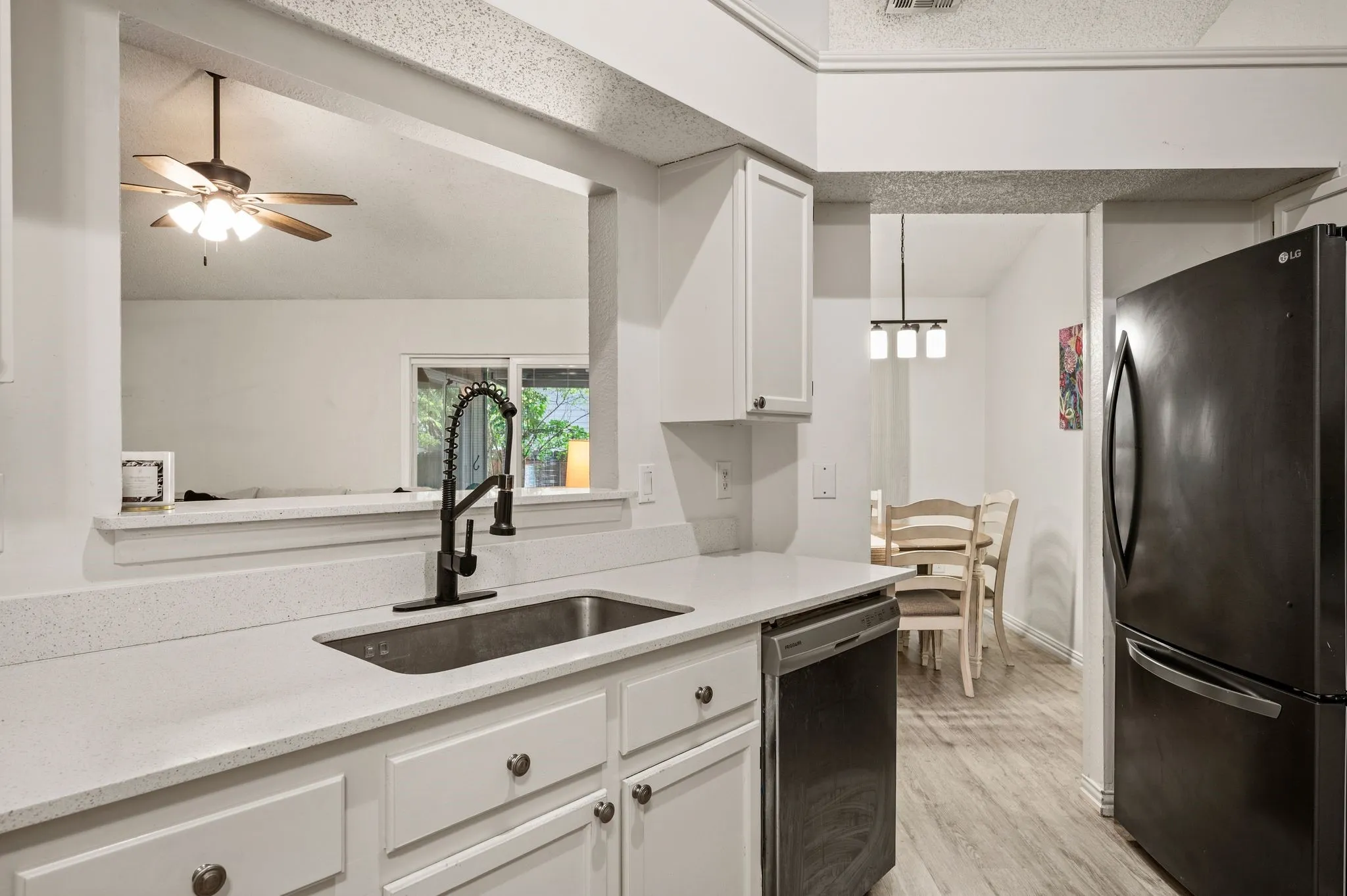 Modern kitchen featuring white cabinetry with brushed nickel hardware, a stainless steel undermount sink with matte black gooseneck faucet, and white quartz countertops