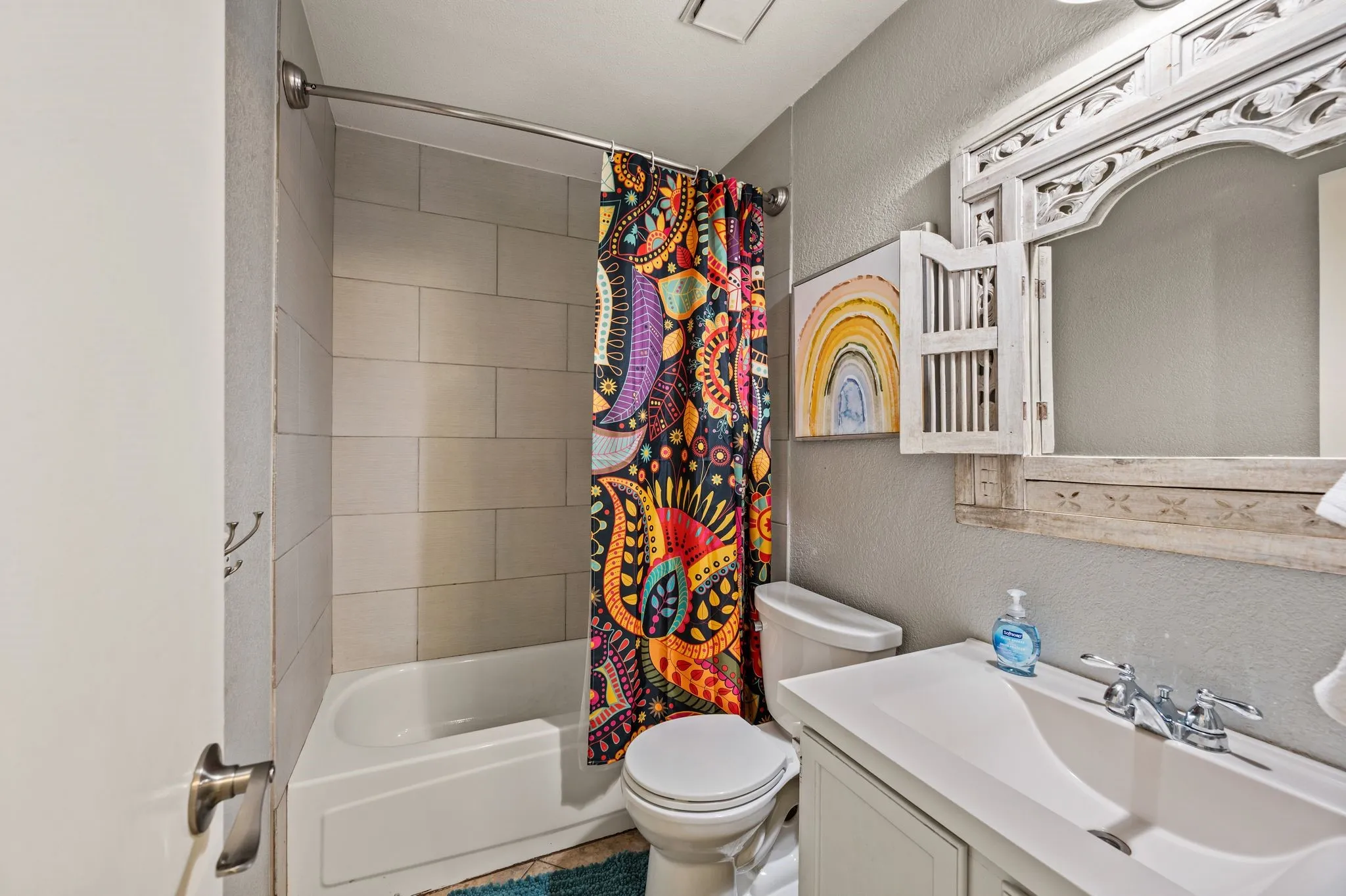 Bathroom featuring a white vanity with integrated sink, chrome faucet, white toilet, and a tiled shower-tub combination