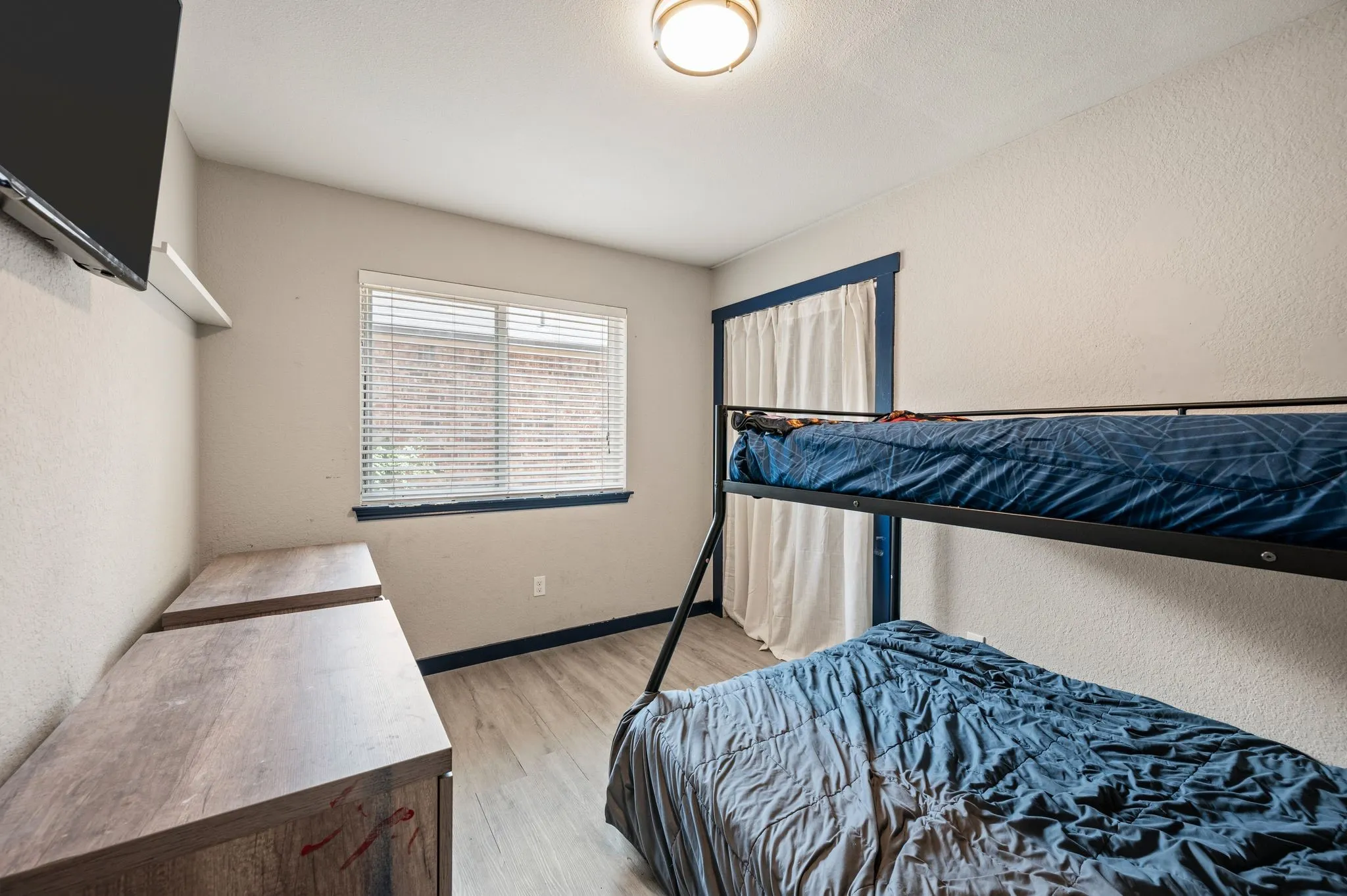 Room featuring wood-finish flooring, a window with blinds, and a ceiling-mounted light fixture