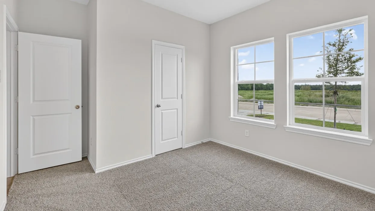 Bright interior space featuring two panel doors, light gray wall paint, and gray carpet flooring