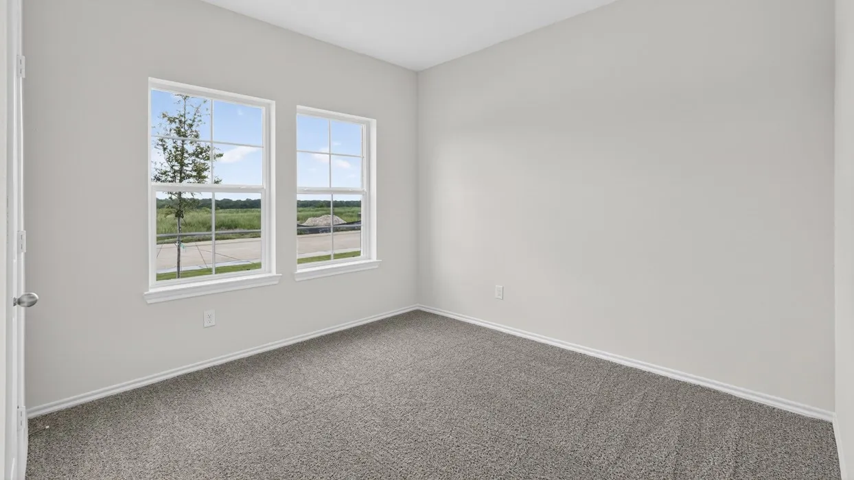 Light-filled room featuring two multi-pane windows, neutral wall tones, and gray carpeting