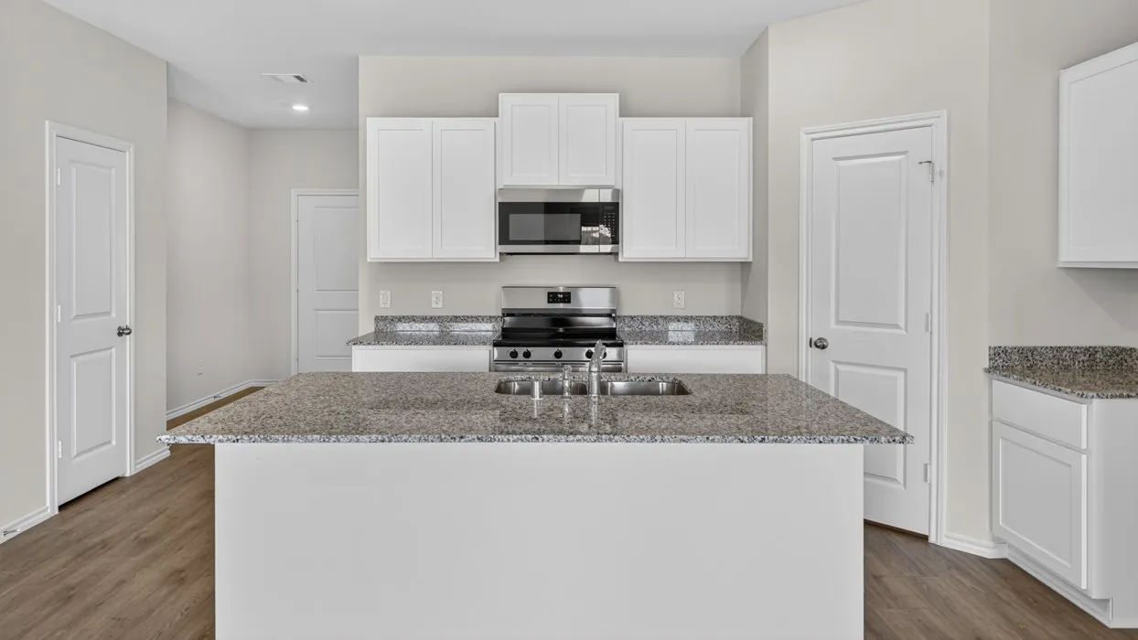 Kitchen featuring a central island with an undermount sink, granite countertops, white cabinetry, stainless steel appliances, and wood-finish flooring
