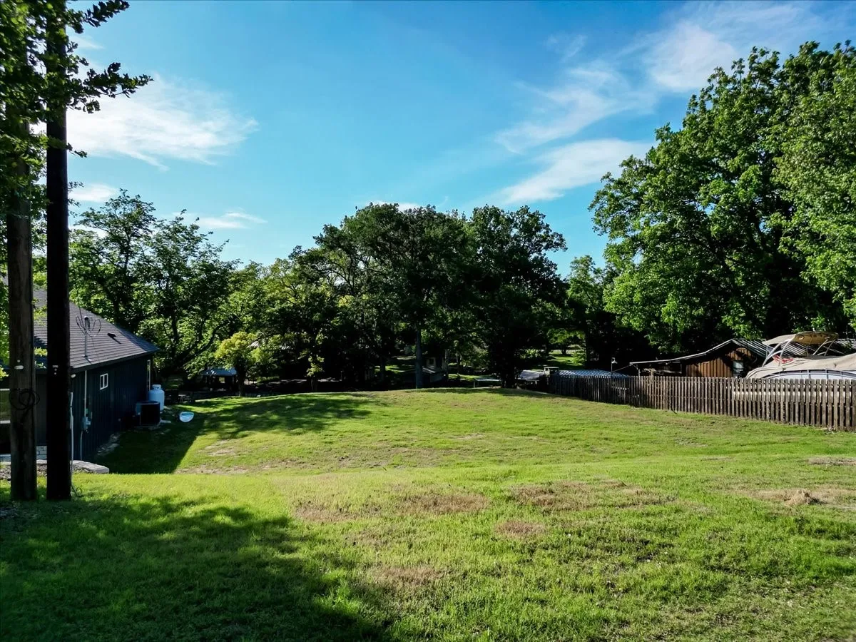 Expansive grassy lot bordered by mature trees and a wood picket fence
