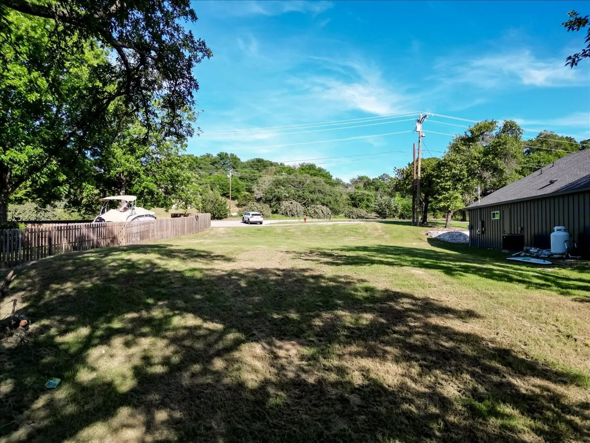 Expansive grassy lawn with established trees and partial wood fencing