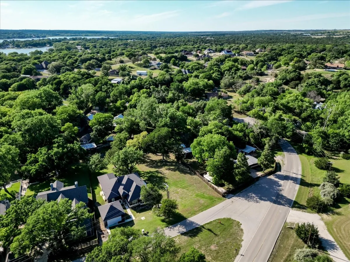 Aerial overview showcasing a residential neighborhood with extensive tree coverage and a distant body of water