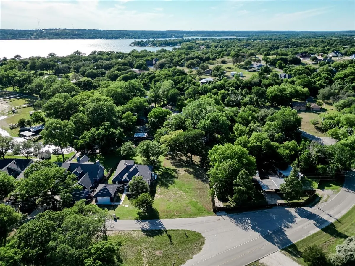 Expansive lot featuring mature trees and established residences, bordered by paved roads