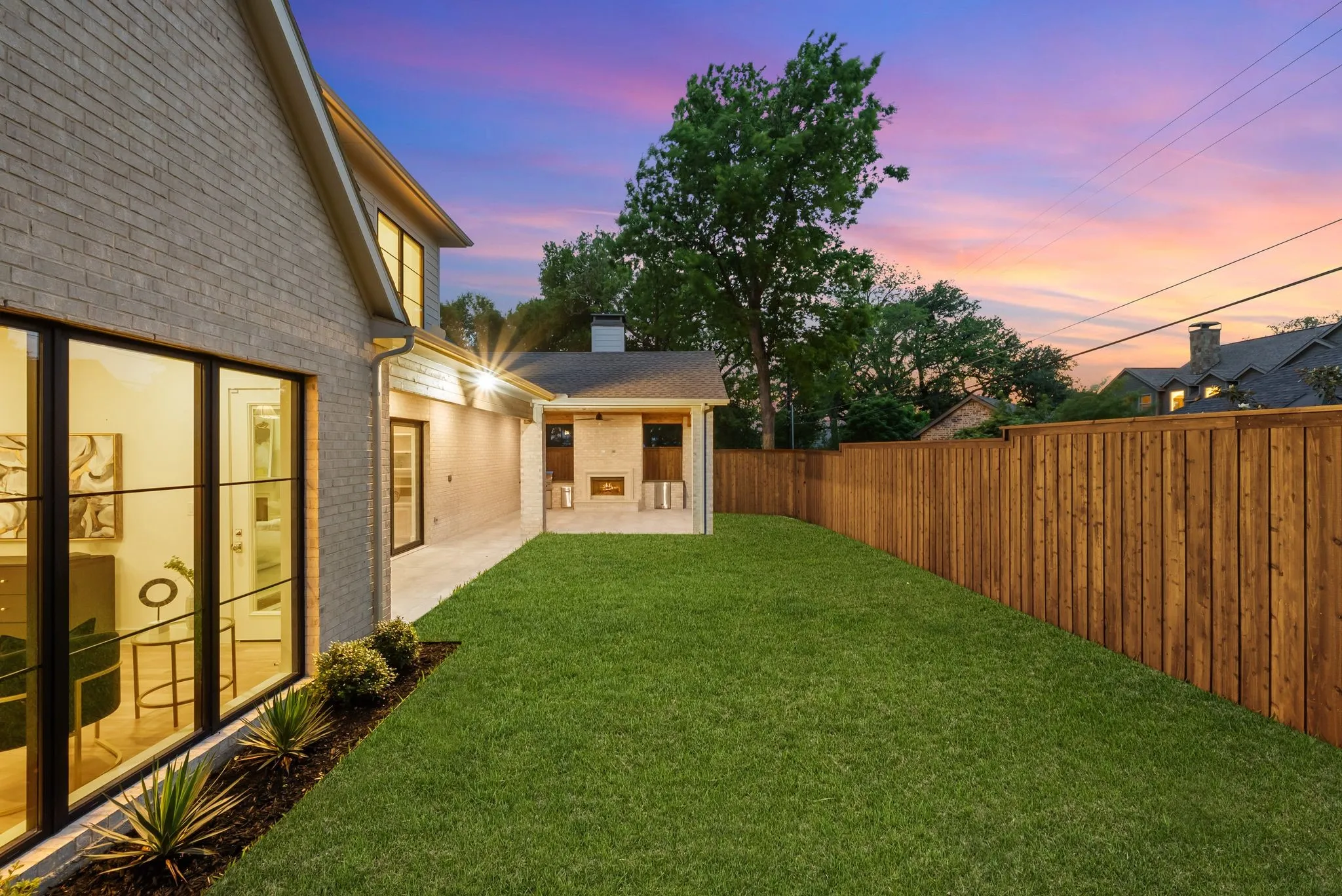 Expansive backyard with a manicured lawn, full wood privacy fence, and a dedicated patio area