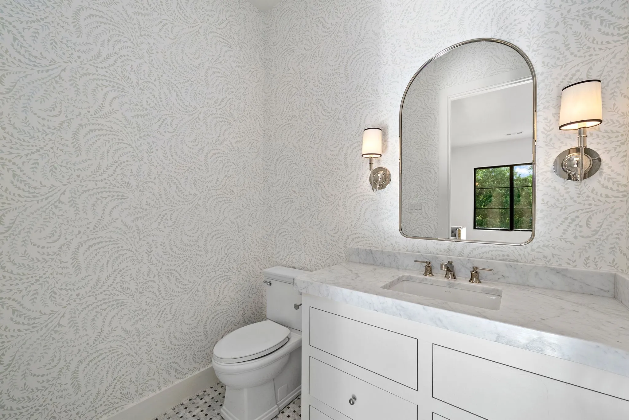Powder room featuring patterned wallpaper, a white vanity with paneled cabinetry, a rectangular undermount sink, and a white stone countertop