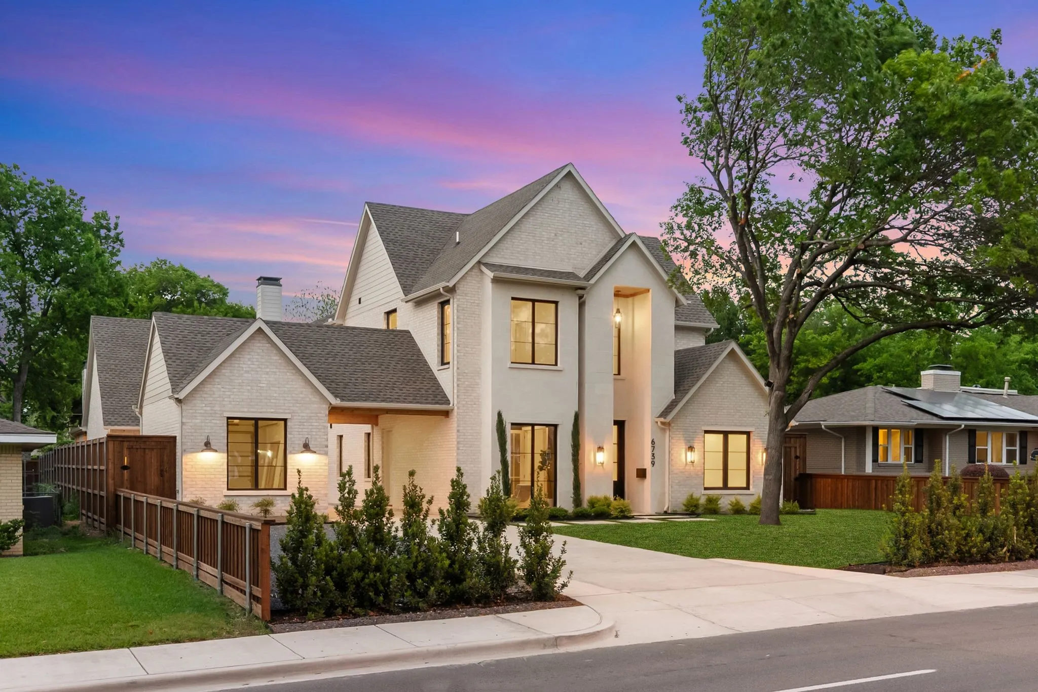 Contemporary residence featuring a light-colored stucco exterior, dark-framed windows, and a prominent peaked roofline