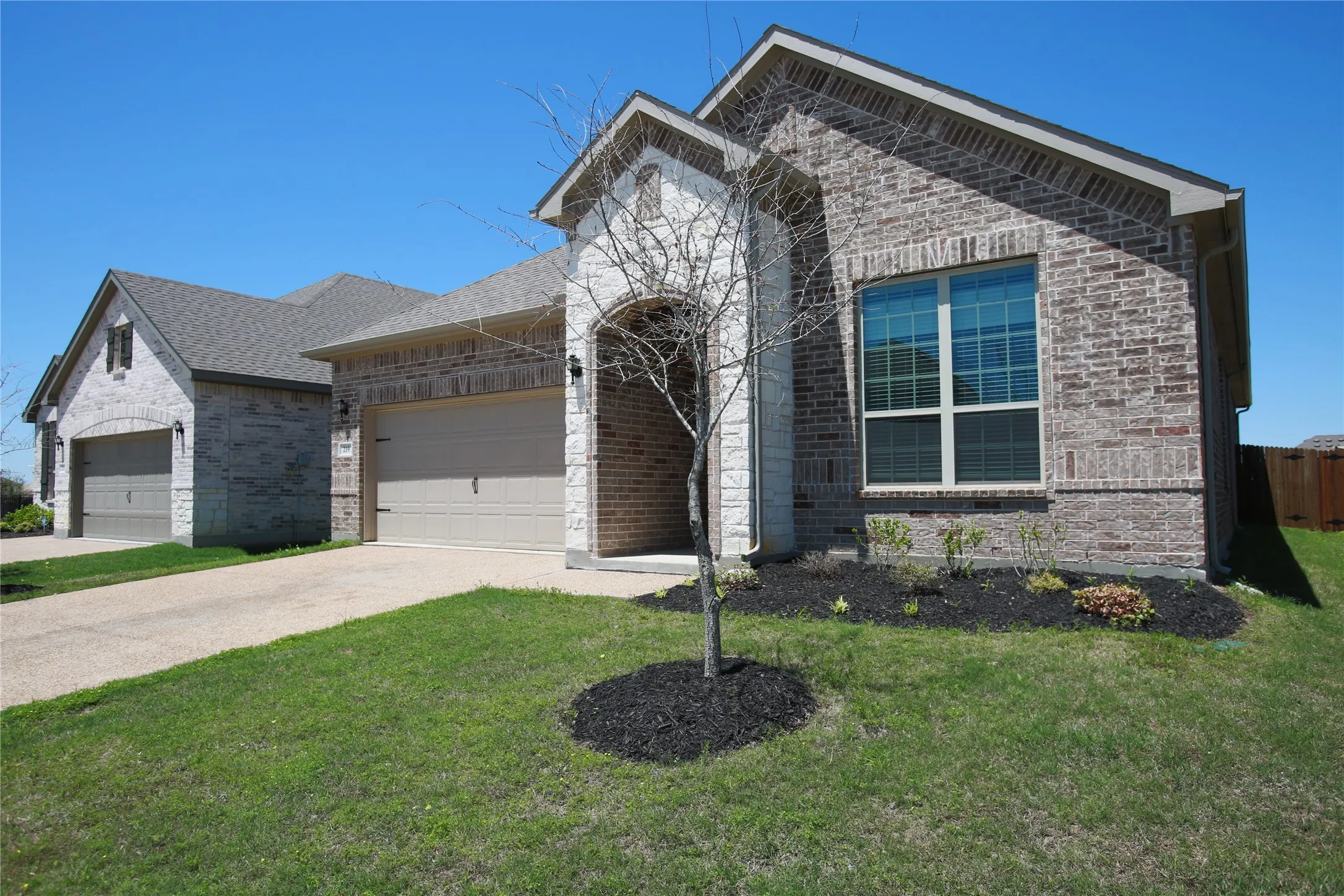 Brick and stone facade featuring an arched entryway and a two-car garage