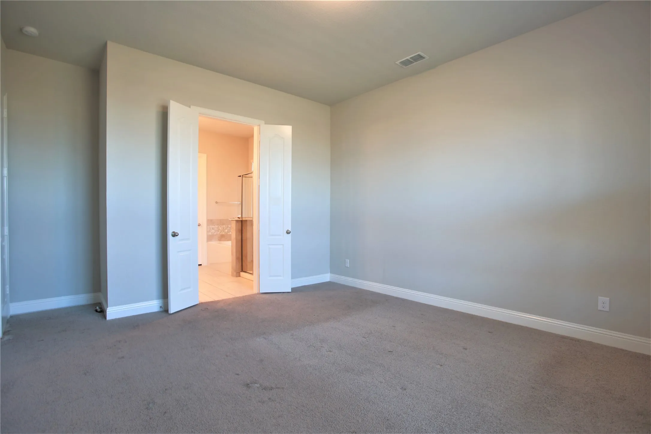 Carpeted interior room with light-toned walls and white baseboards