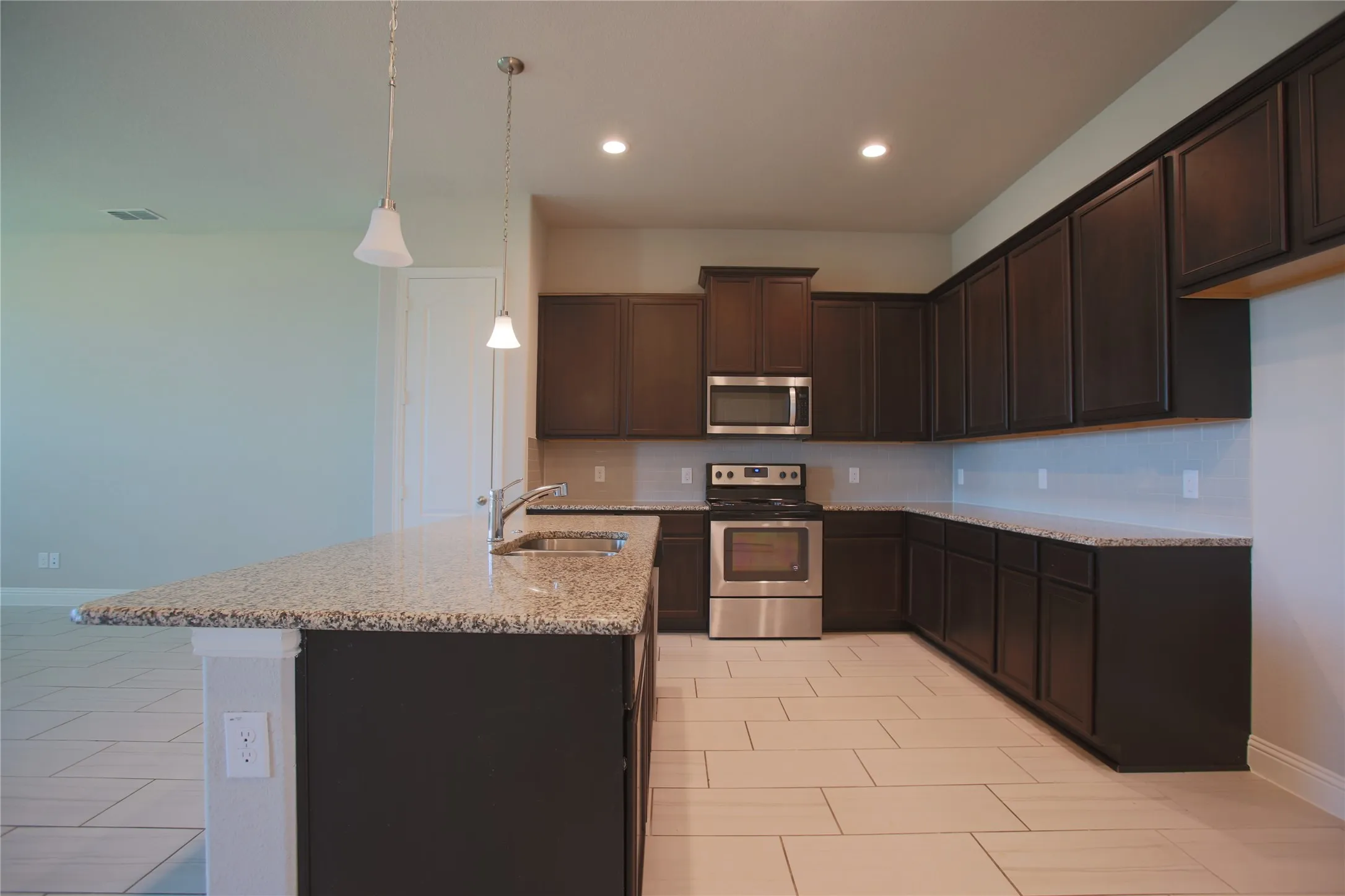 Kitchen featuring a central island with a granite countertop, dual pendant lighting, and an undermount sink