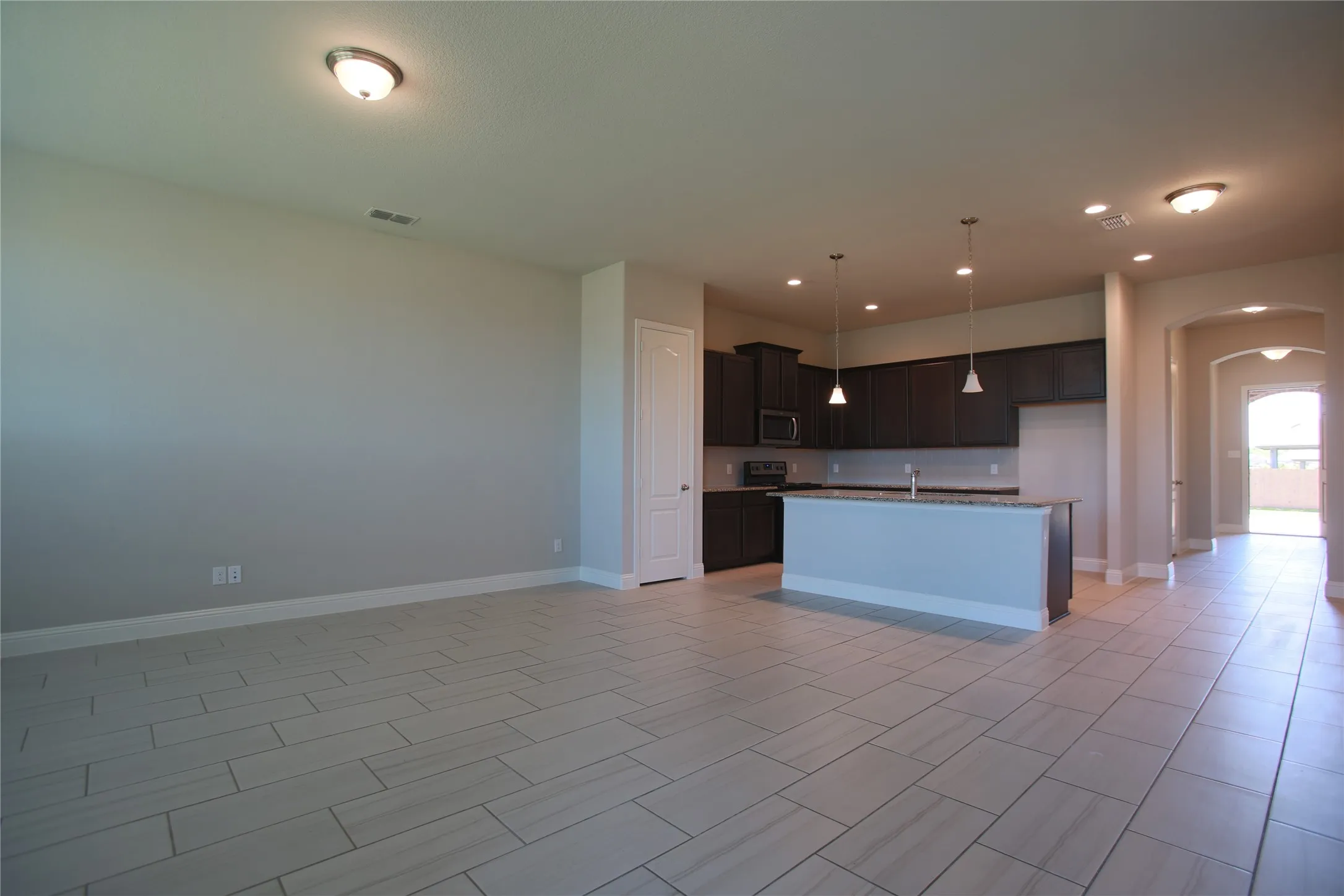 Open-concept living area with large format tile flooring and recessed lighting