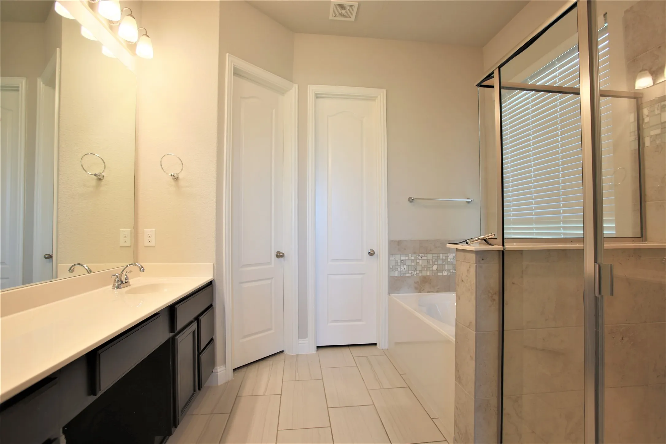 Dual vanity with dark wood-finish cabinetry, a single basin, and chrome faucet