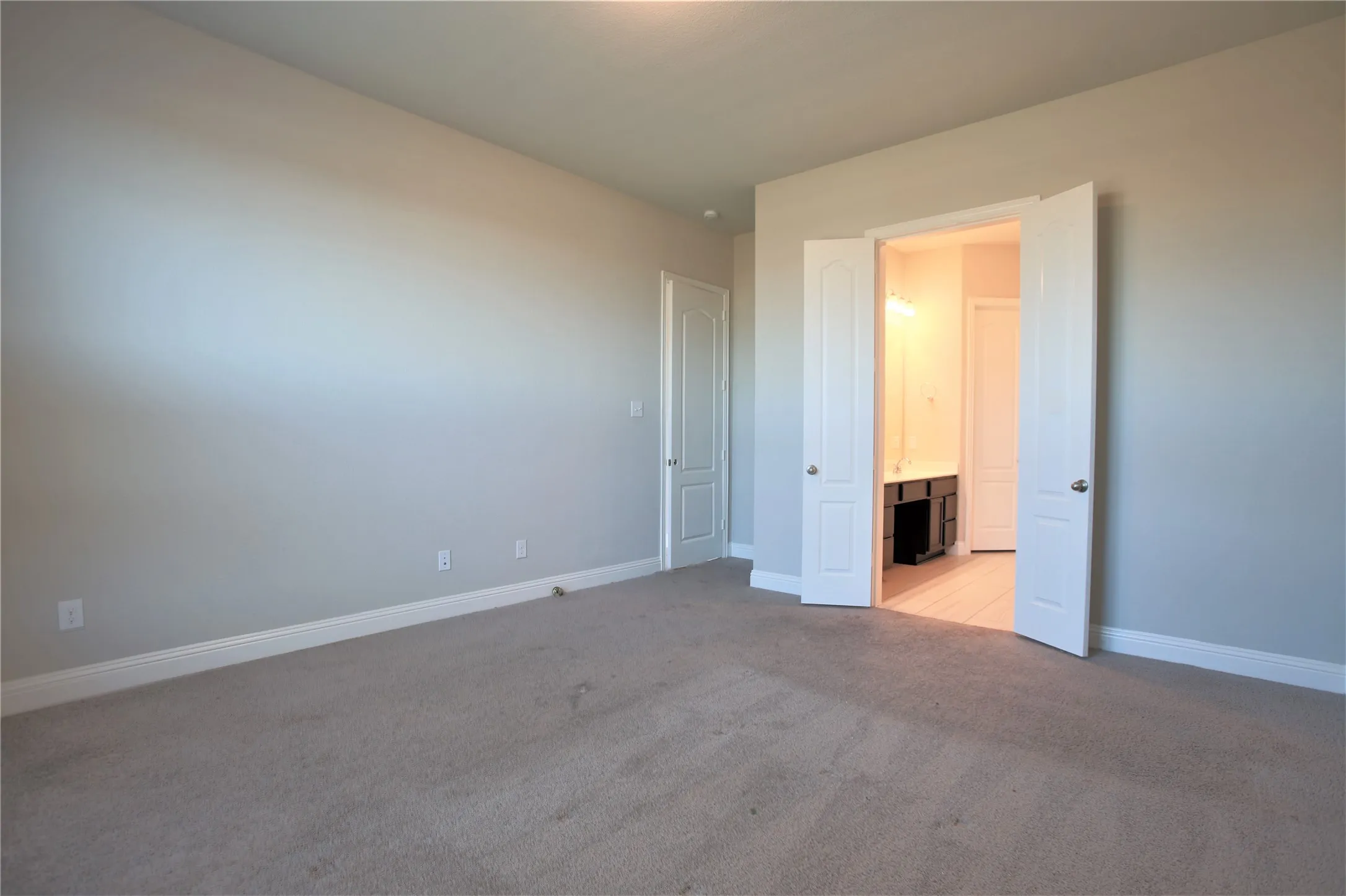 Spacious room with neutral-toned carpet flooring and light gray walls