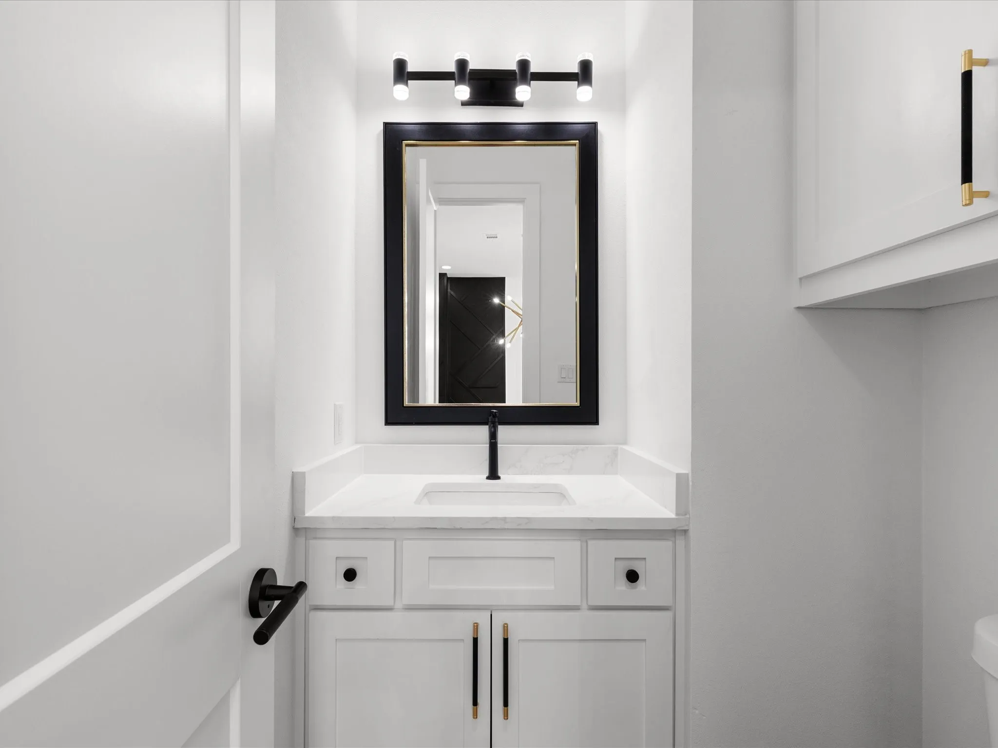Bathroom vanity featuring a white shaker-style cabinet, a white countertop, and a rectangular undermount sink with a matte black faucet