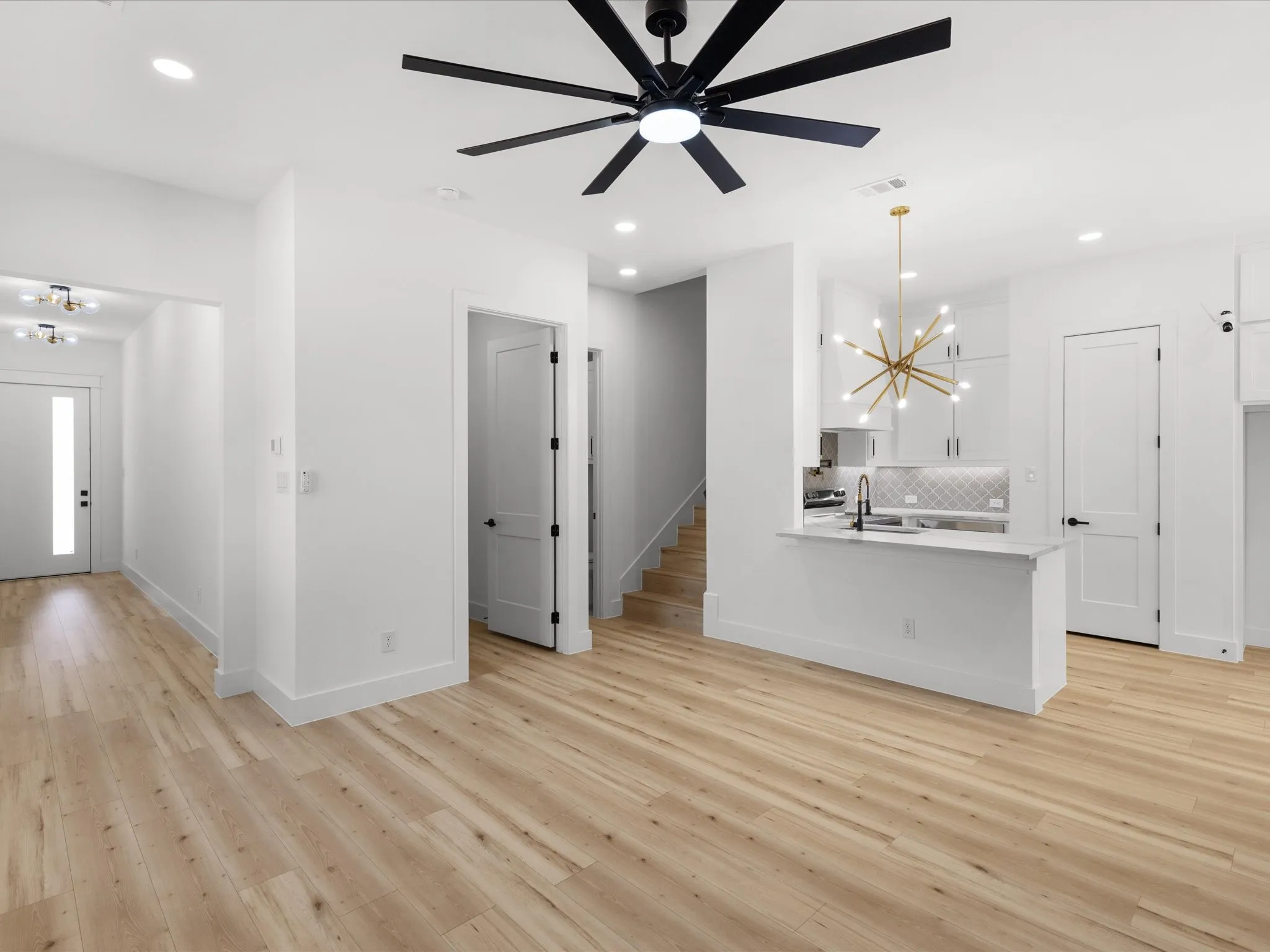 Open-concept living space featuring wood-finish flooring, a modern black ceiling fan, and recessed lighting