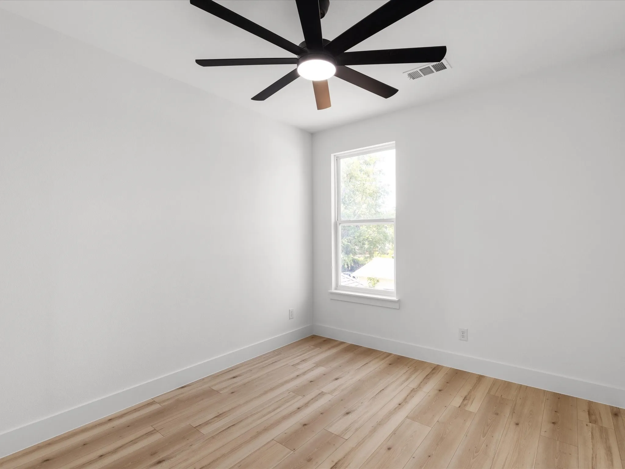 Room featuring wood-finish flooring, a single window, and a ceiling fan with integrated lighting