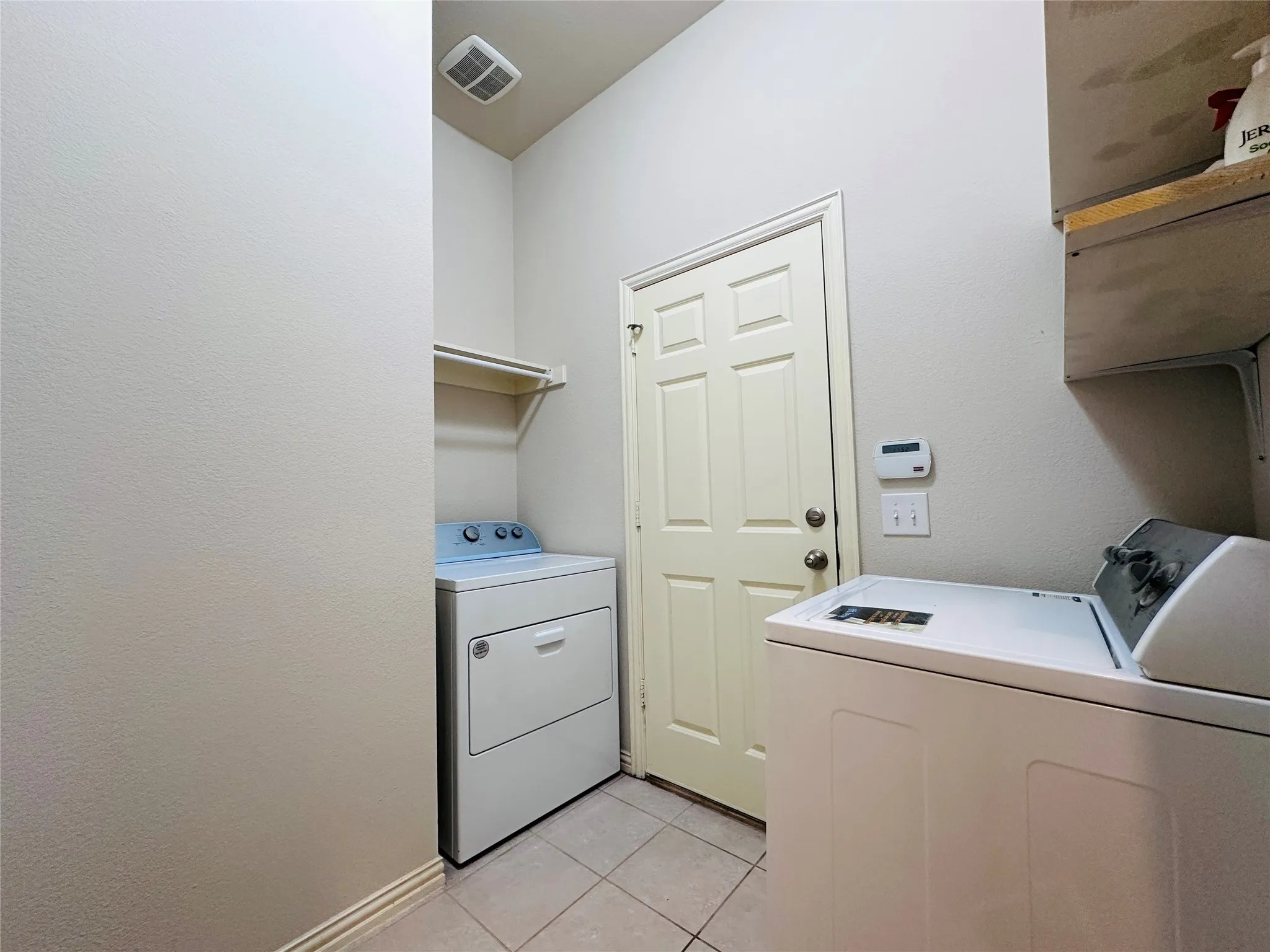 Utility room featuring light-toned walls, tile flooring, and a paneled door