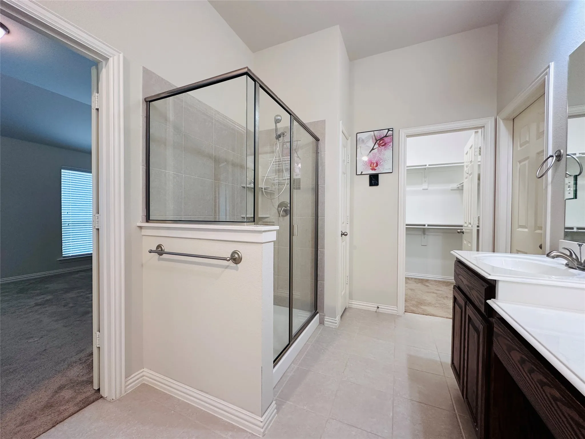 Bathroom featuring a glass-enclosed shower with tile surround, a dark wood-finish vanity with an integrated sink, and tile flooring