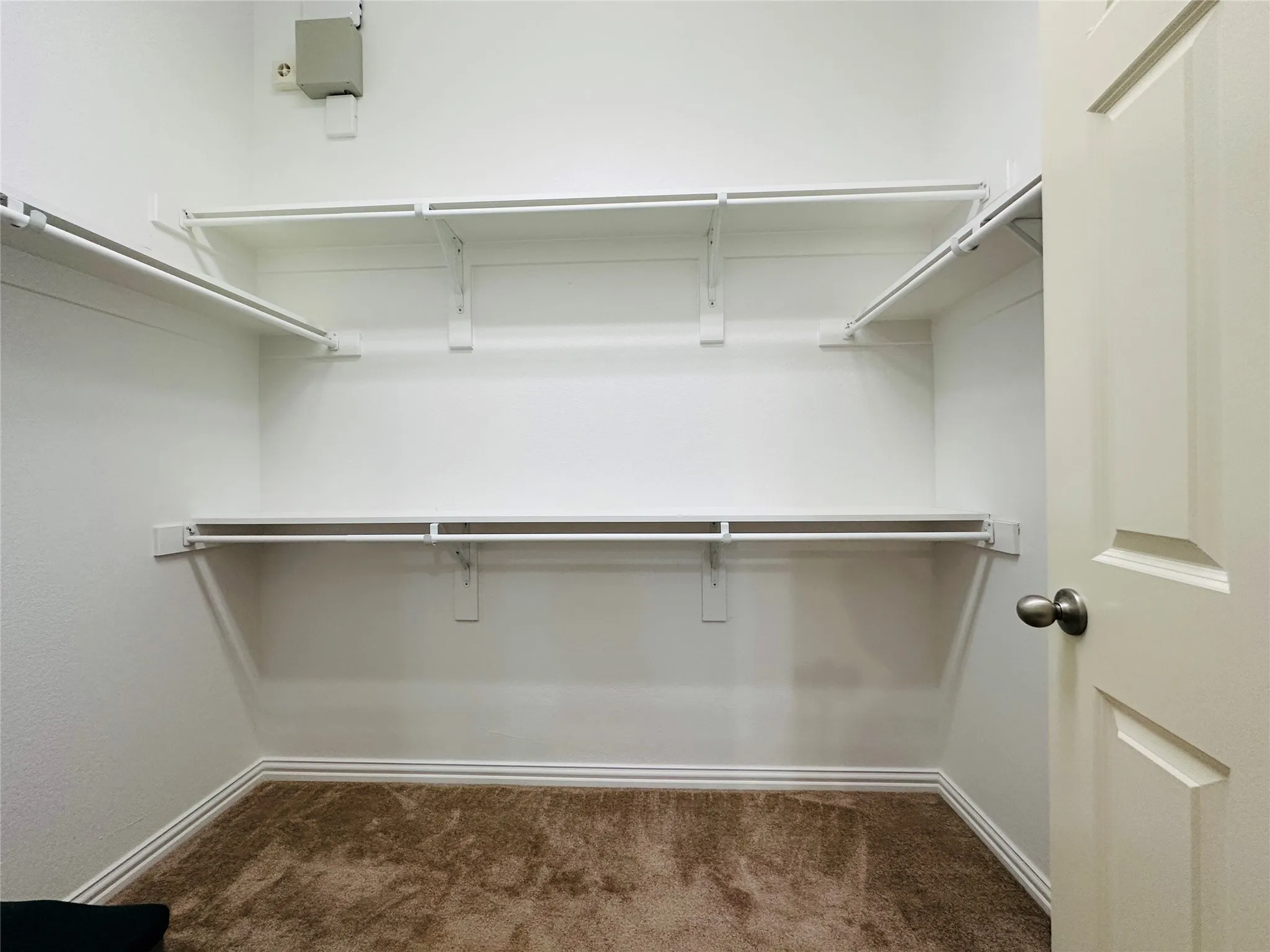 Walk-in closet with carpet flooring, white wire shelving, and hanging rods