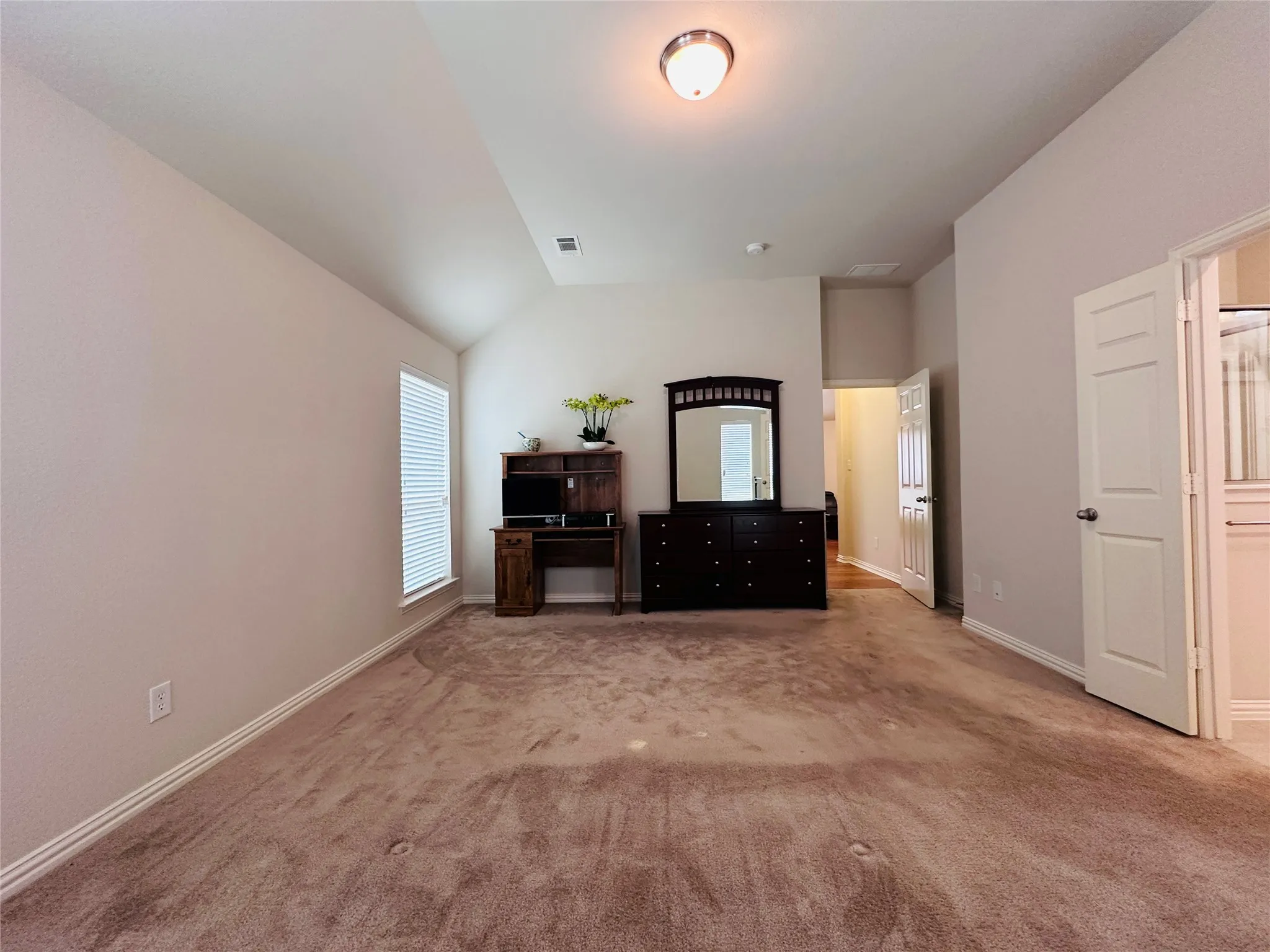 Spacious room featuring vaulted ceilings, light neutral wall tones, and carpet flooring