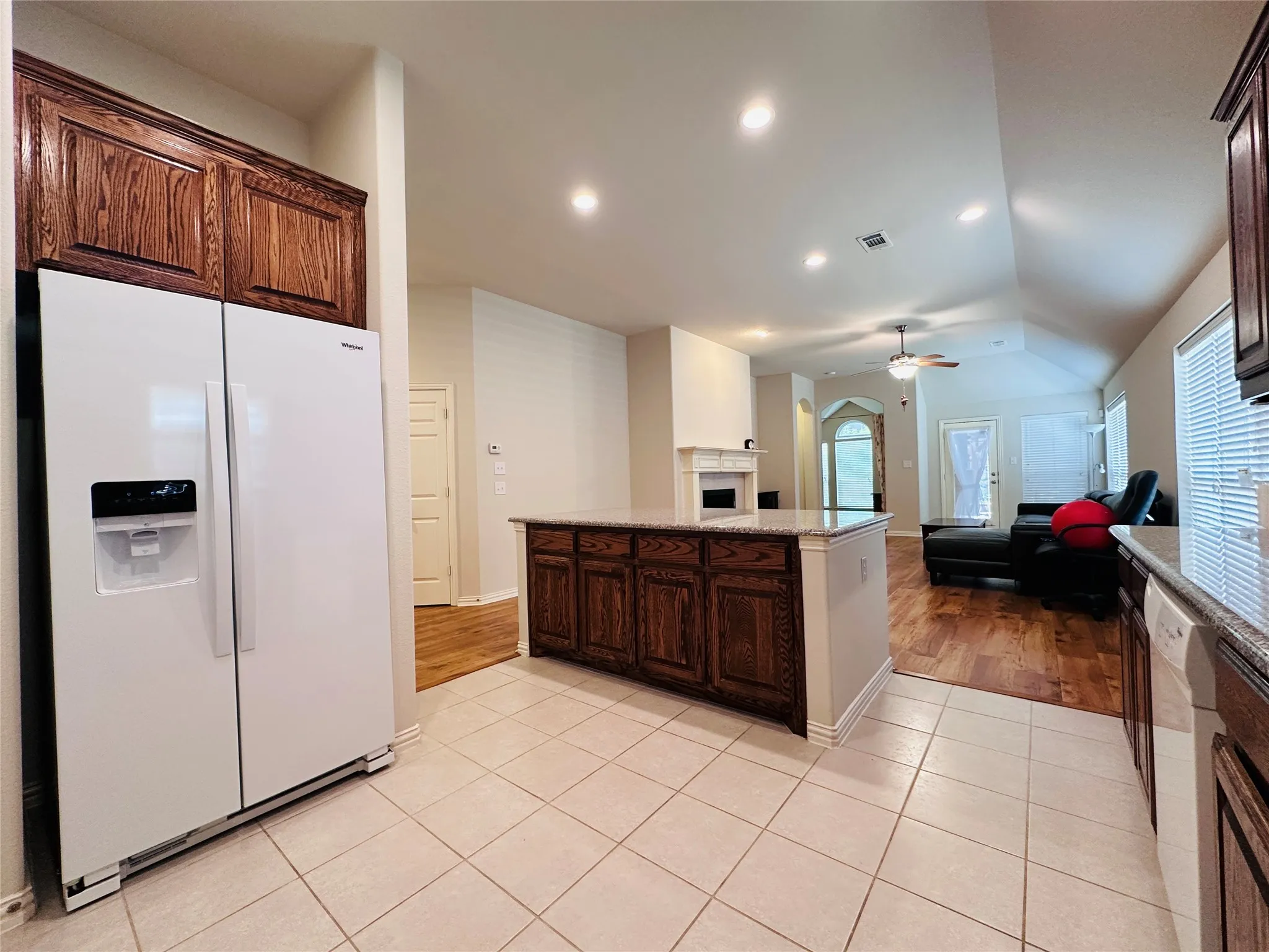 Open-concept kitchen featuring tile flooring, granite countertops, wood-finish cabinetry, and recessed lighting