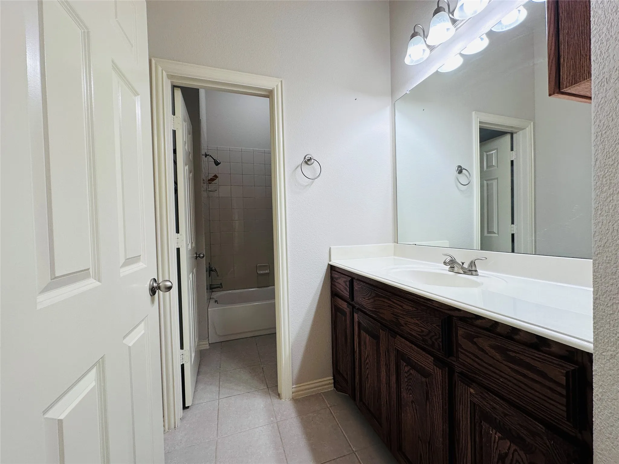Bathroom vanity featuring wood-finish cabinetry, a white countertop with integrated sink, and a large mirror