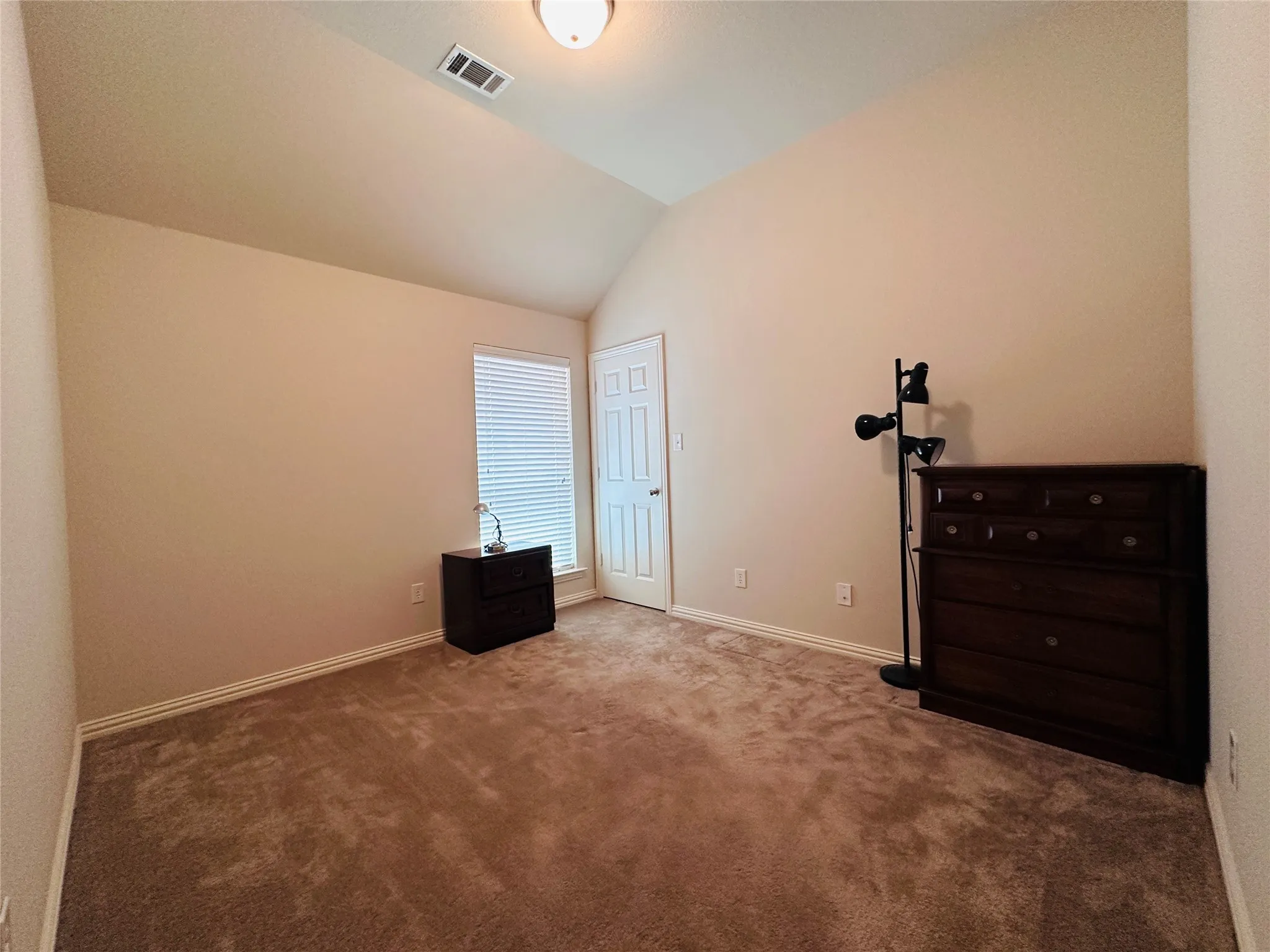Bedroom featuring vaulted ceilings, neutral wall tones, and plush carpet flooring