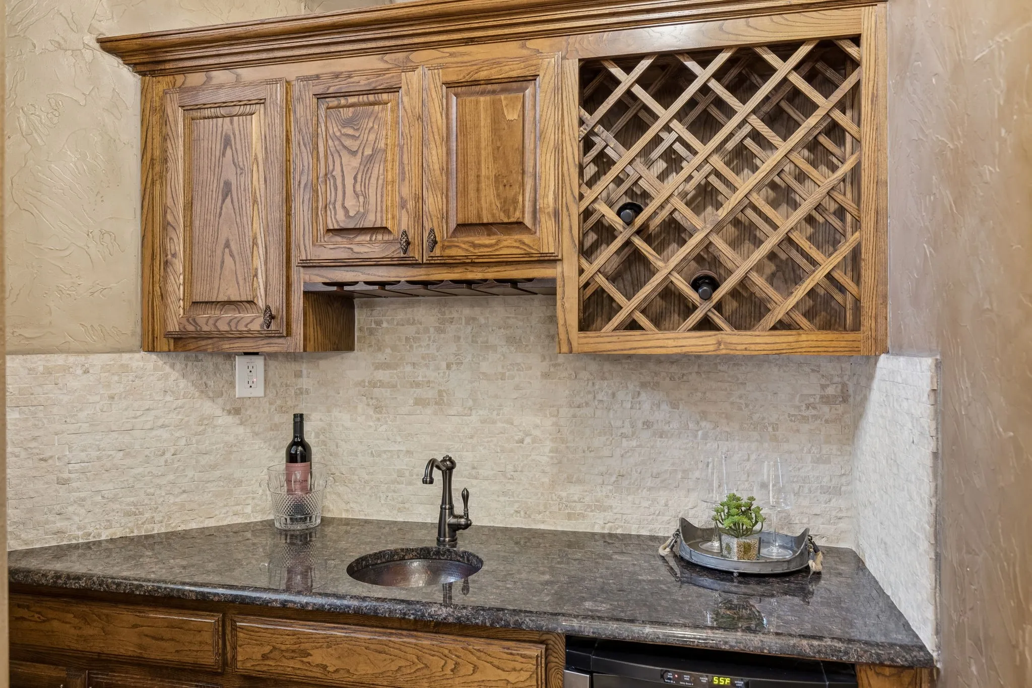 The thoughtful built-in features in this home are fabulous. Drop down bar with beverage frig, tumbled stone backsplash and serving sink.