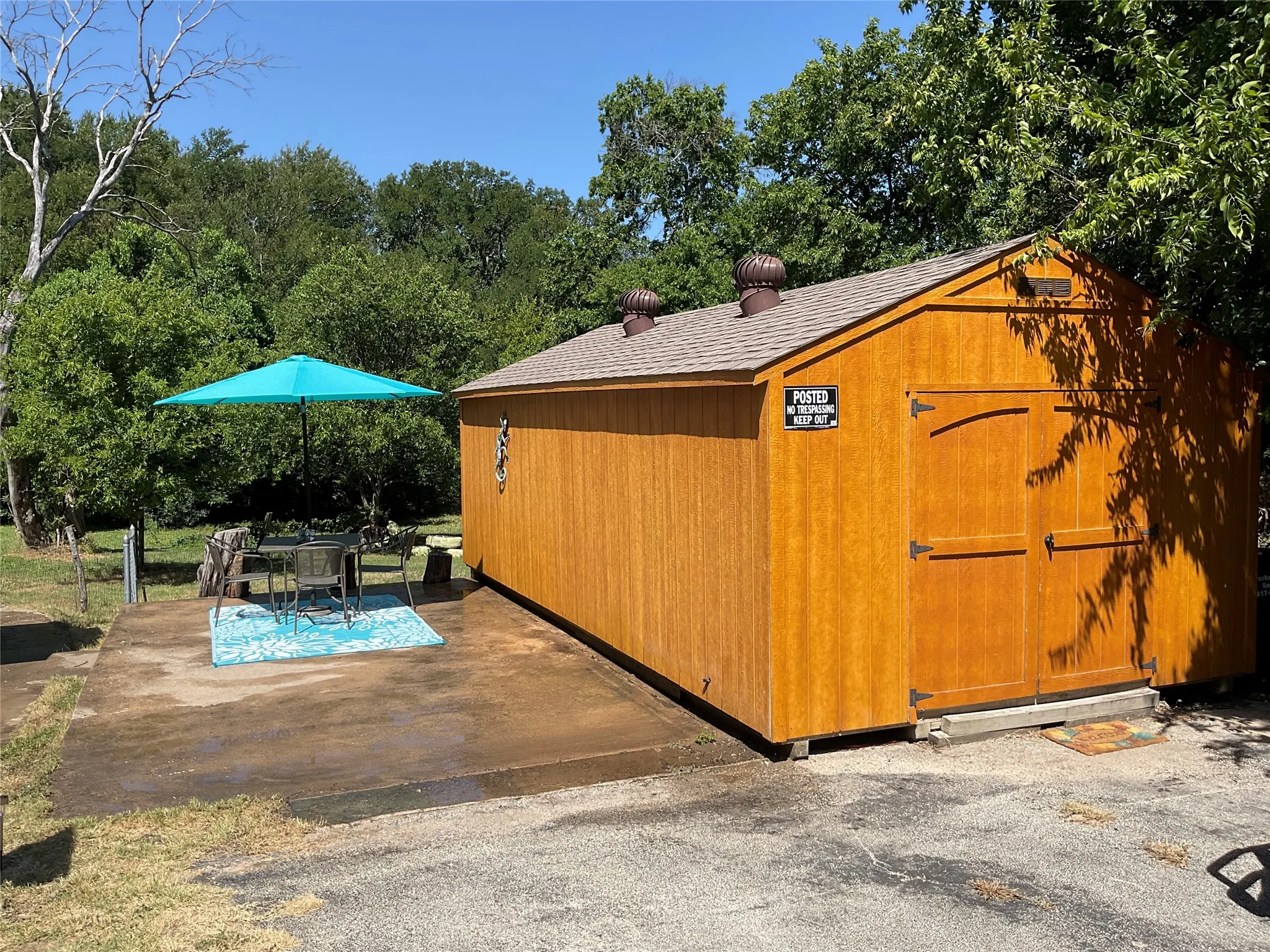 Wood-sided shed with a shingled roof featuring twin turbine vents and double front doors