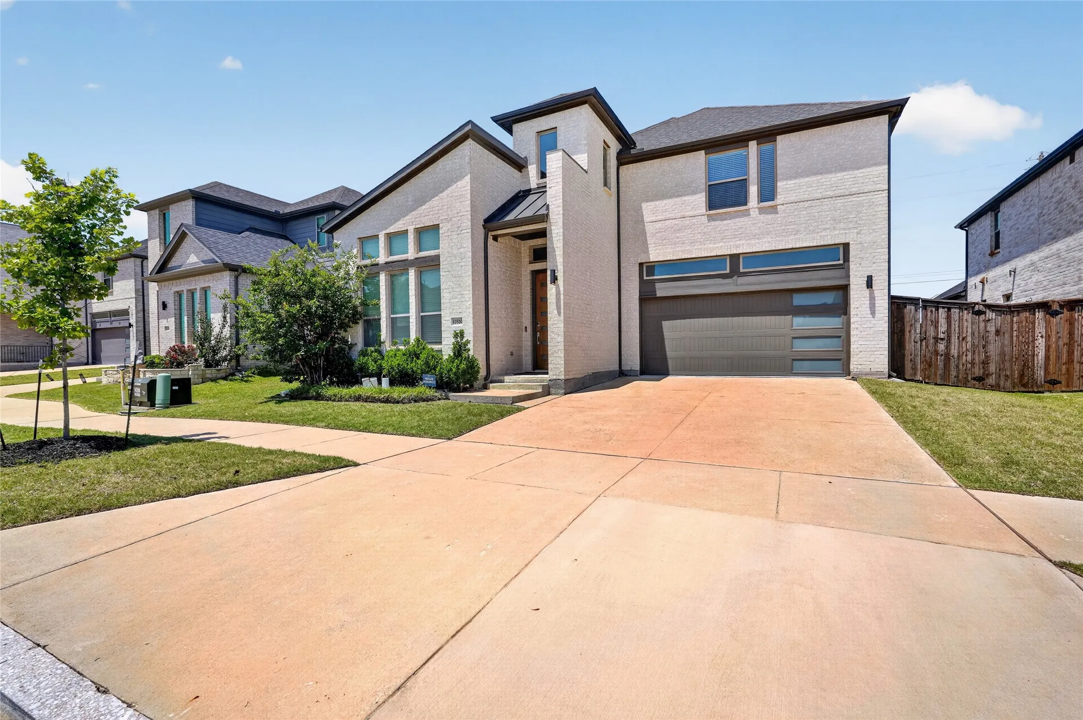 Contemporary two-story exterior featuring a light-toned brick facade and dark trim accents