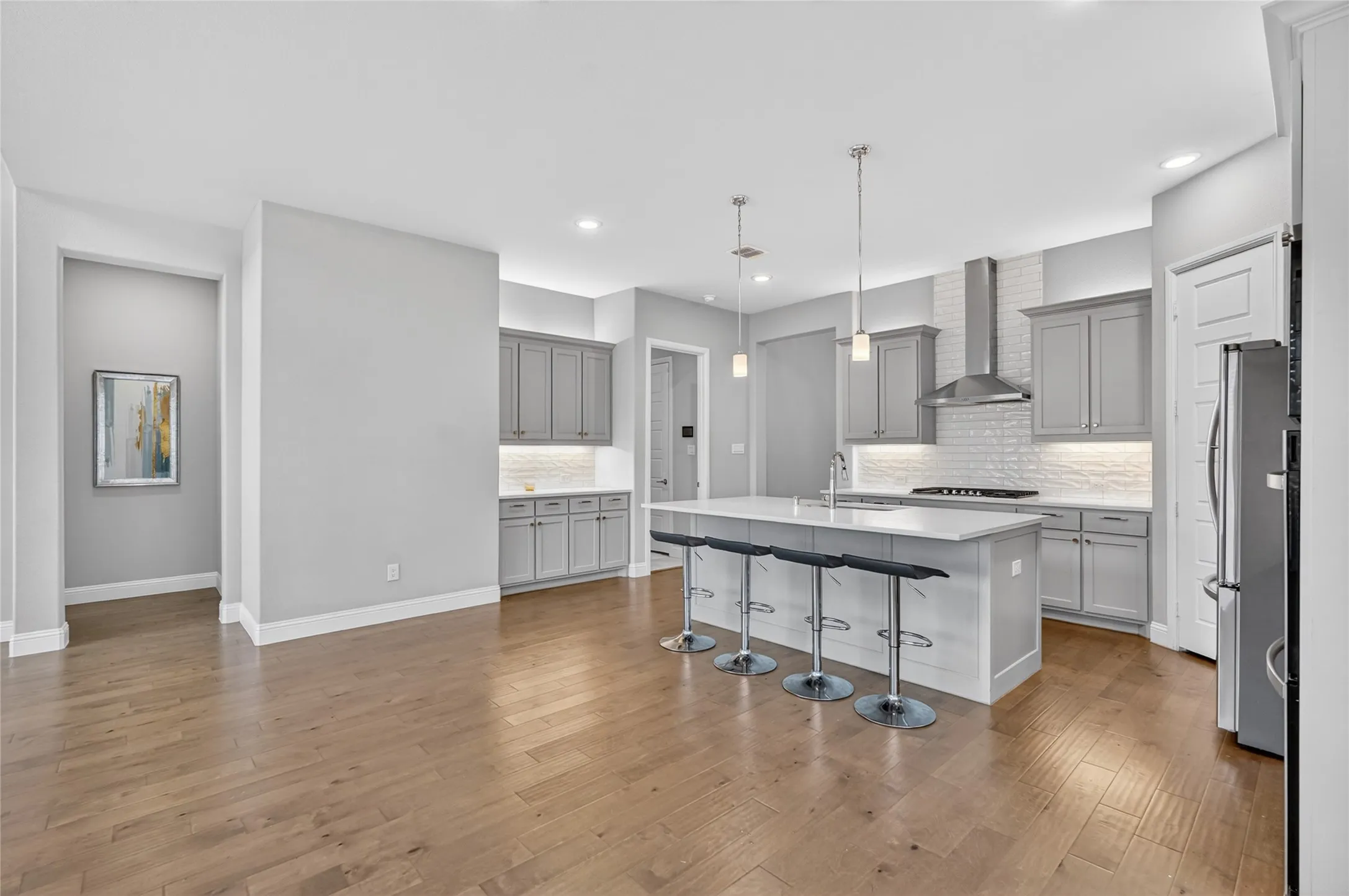 Gourmet kitchen featuring a large central island with seating, pendant lighting, stainless steel appliances, and abundant cabinetry