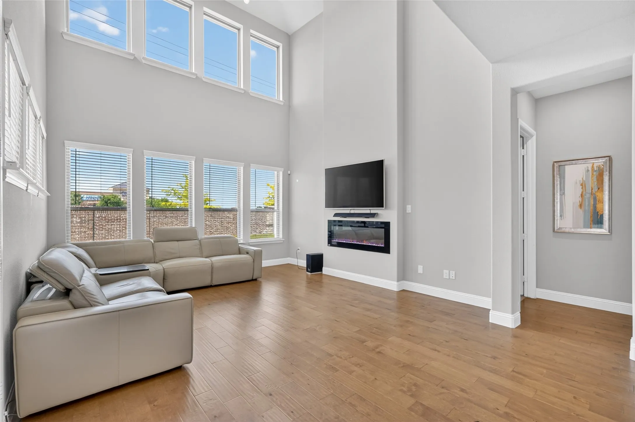 Living area featuring high ceilings, wood-finish flooring, and multiple windows with blinds