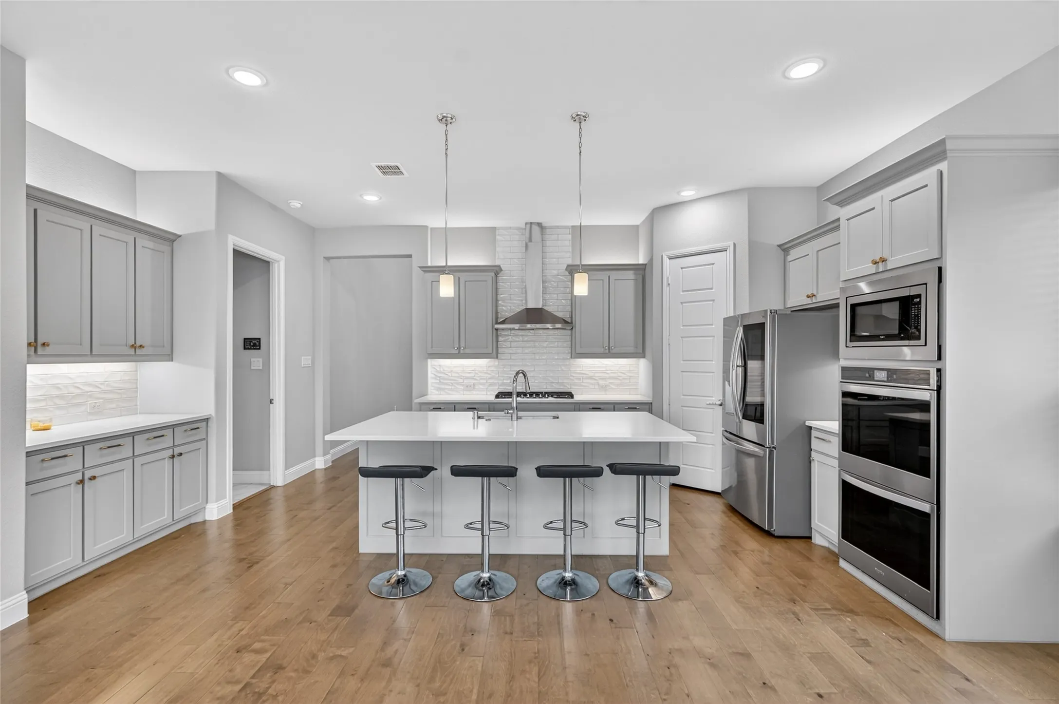 Spacious kitchen featuring an expansive central island, light wood-finish flooring, recessed lighting, and stainless steel appliances