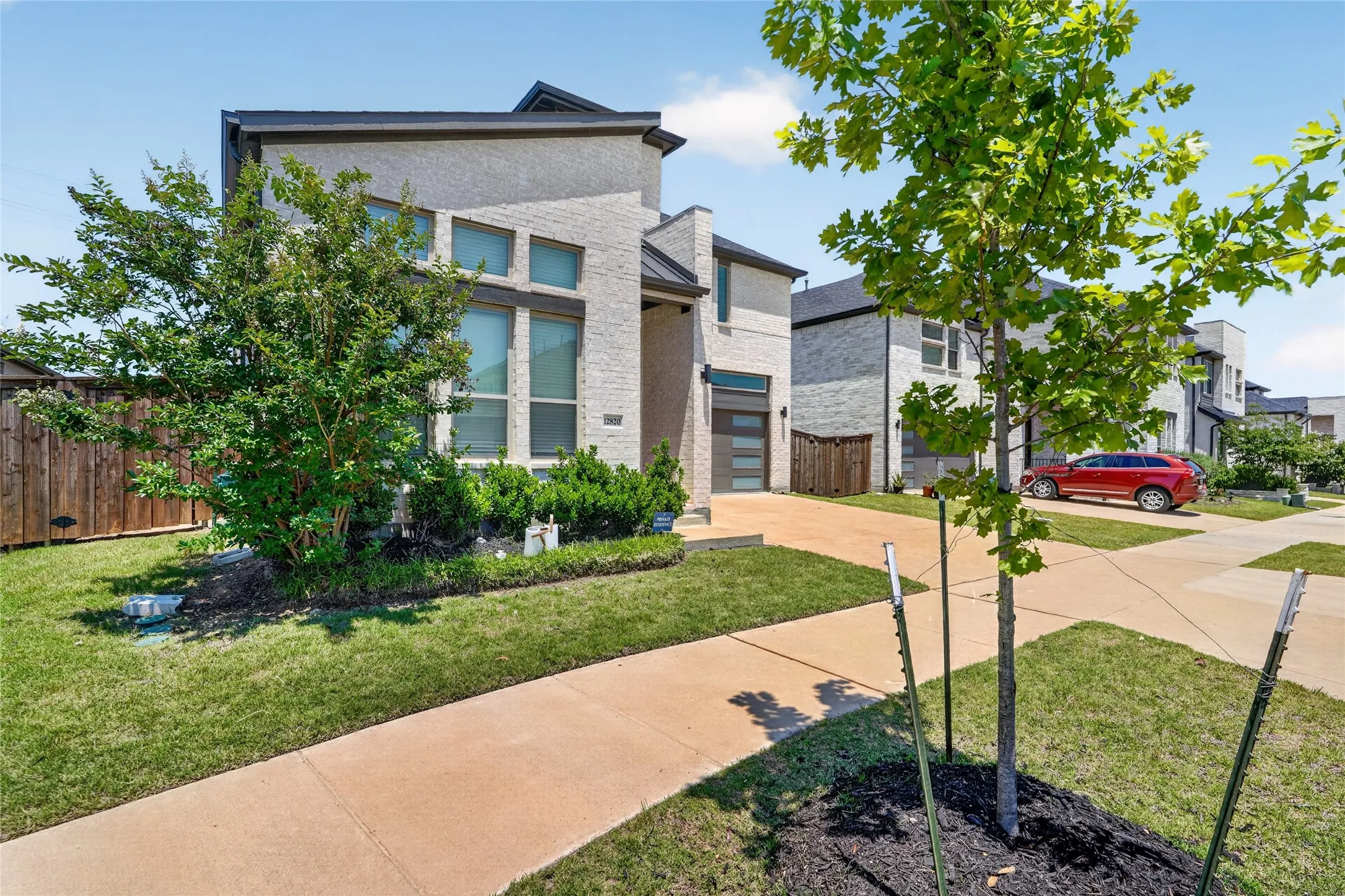 Modern stucco and brick exterior featuring a multi-pane front door, a two-car garage with a frosted glass door, and a concrete driveway