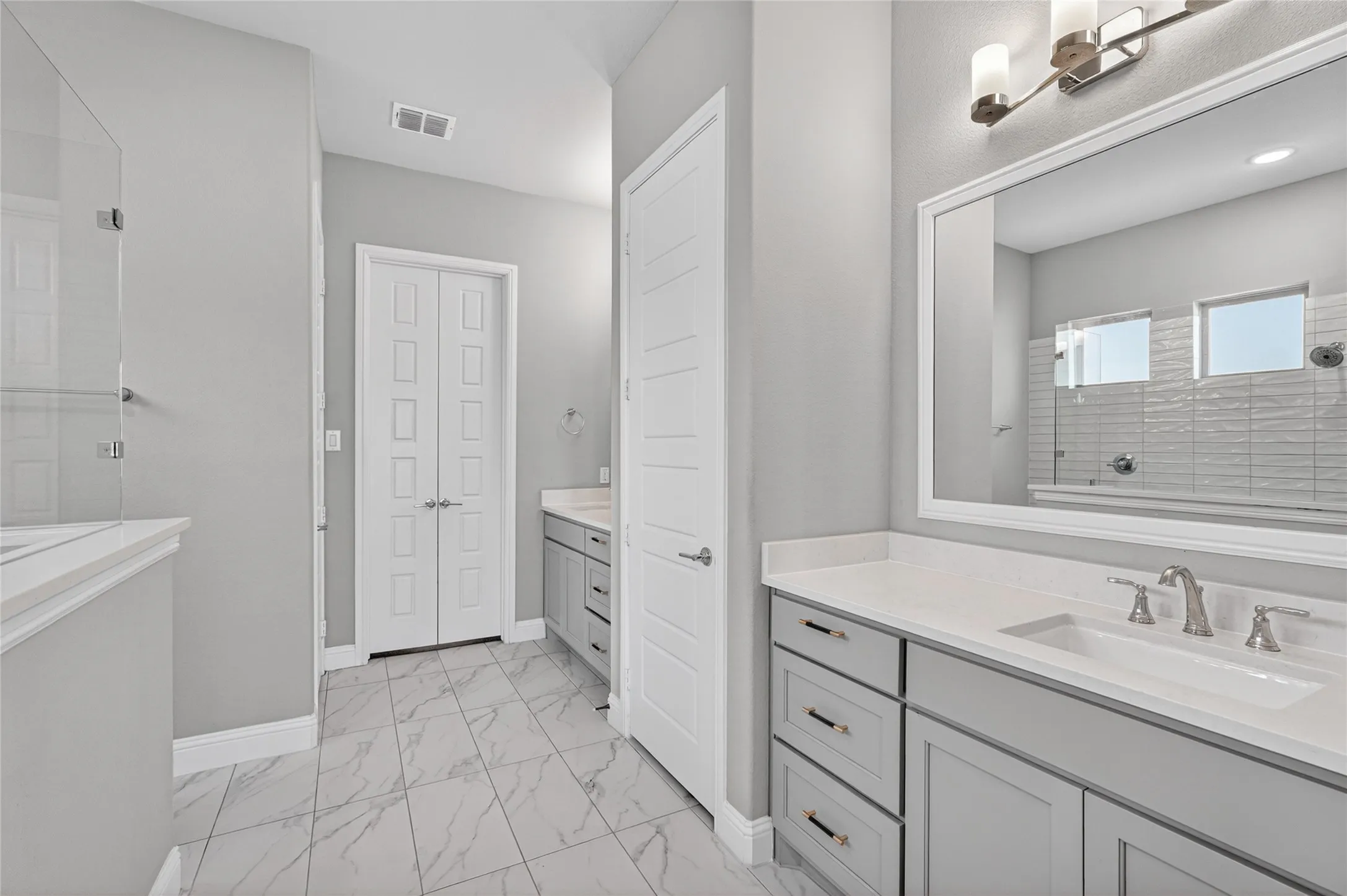 Bathroom featuring a dual vanity with light gray cabinetry, white countertops, and brushed nickel hardware
